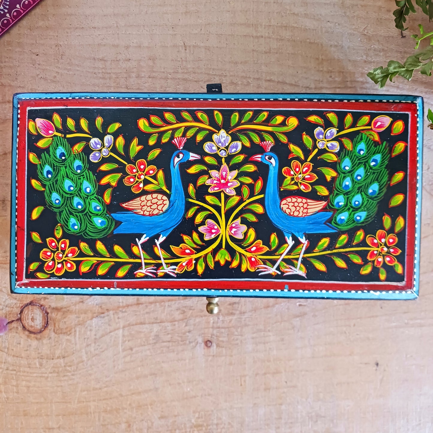 This beautiful hand painted sustainable mango wood box is ideal for keeping your jewellery or keepsakes in. The pretty peacock painting is framed with florals, as are the sides, and a little gold knob at the side for opening. A unique gift of colour and culture.