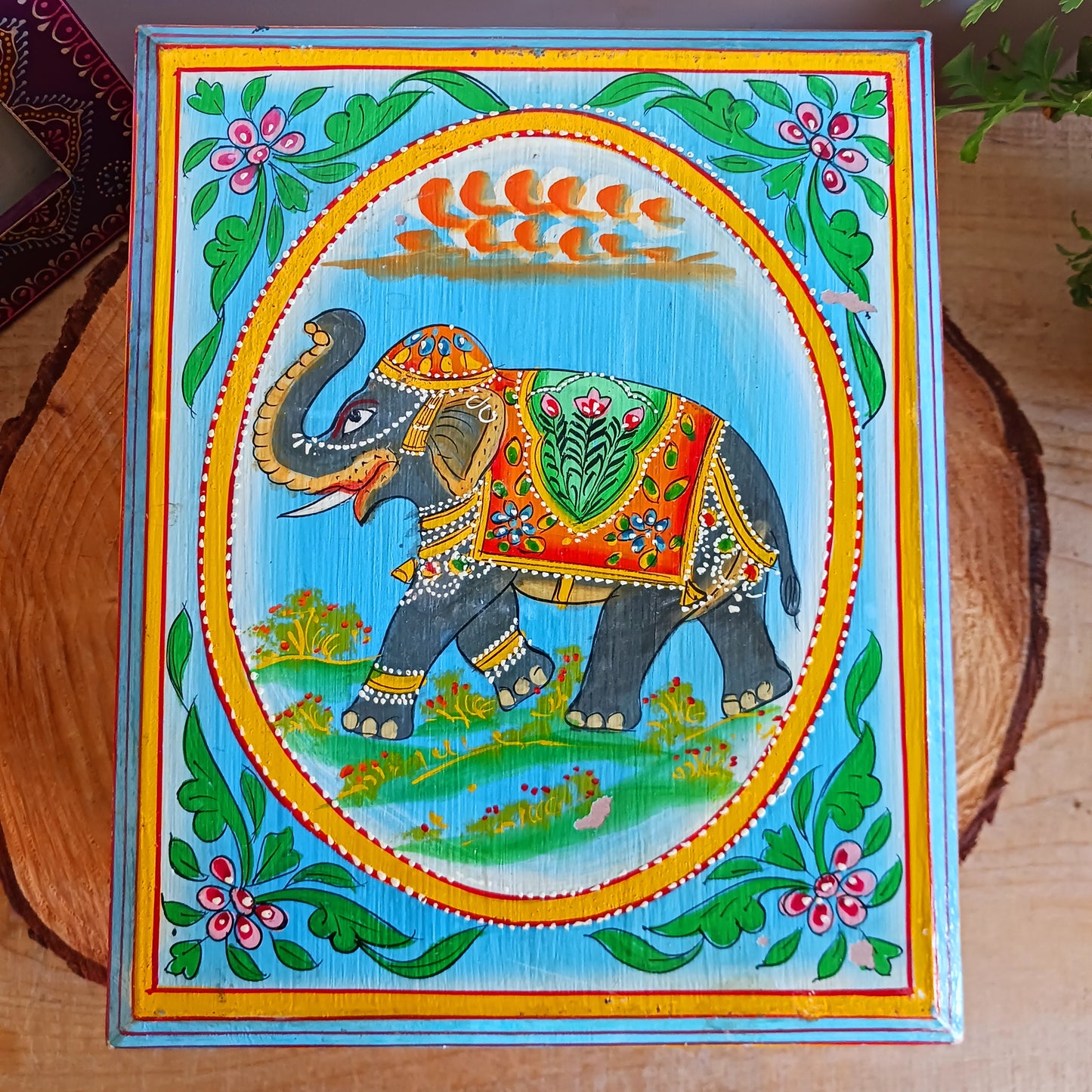 This stunning large Indian jewellery box has been hand painted to perfection in fresh spring-like colours of pastel blue, primrose yellow, pale pink and new season green.&nbsp; The elephant on the lid is in full ceremonial regalia and oval framed in yellow. It comprises a single drawer and top compartment opened by discreet round knobs.  A beautiful addition to any home.