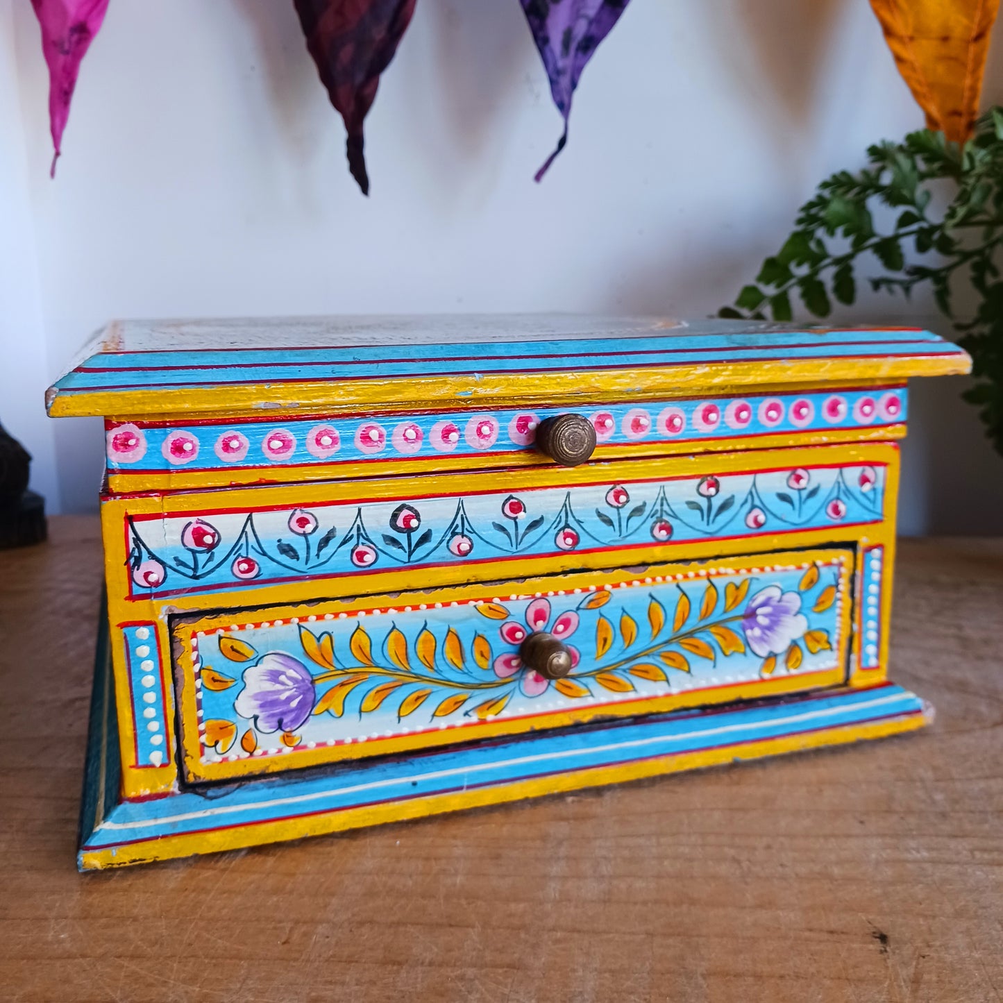 This stunning large Indian jewellery box has been hand painted to perfection in fresh spring-like colours of pastel blue, primrose yellow, pale pink and new season green.&nbsp; The elephant on the lid is in full ceremonial regalia and oval framed in yellow. It comprises a single drawer and top compartment opened by discreet round knobs.  A beautiful addition to any home.