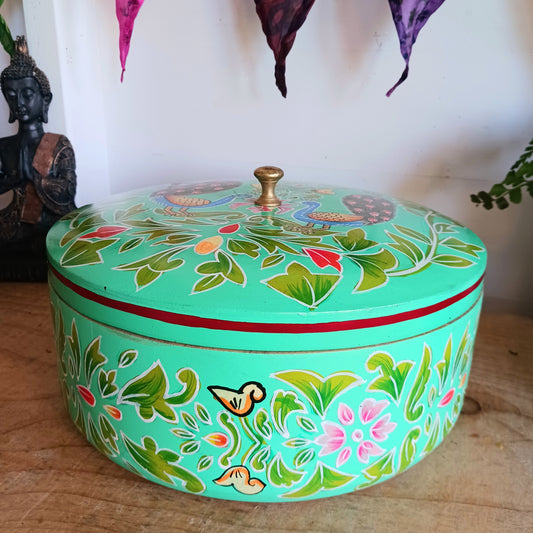 This beautiful large turquoise round Indian wooden box has been hand painted in a peacock design on the pull-off lid. It has a small round gold coloured central knob. Green leaves and pink flowers complete an appealing design.