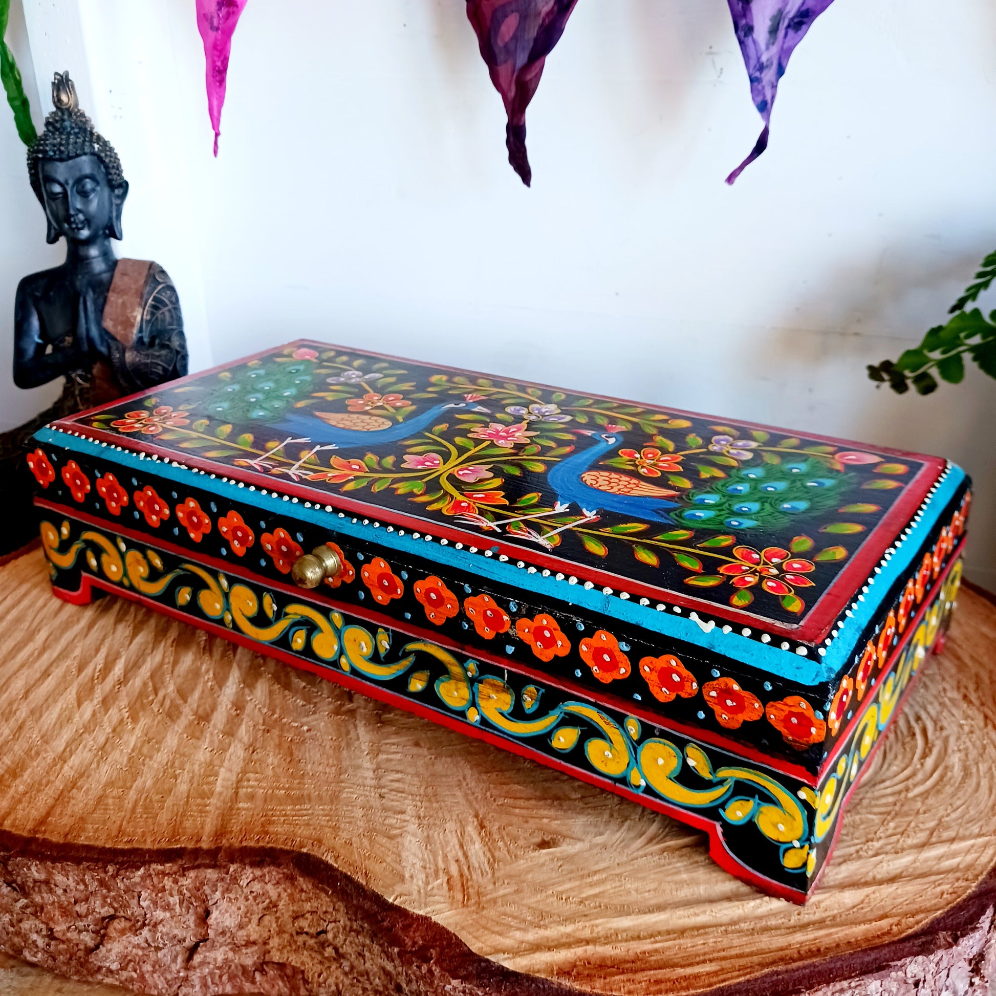 This beautiful hand painted sustainable mango wood box is ideal for keeping your jewellery or keepsakes in. The pretty peacock painting is framed with florals, as are the sides, and a little gold knob at the side for opening. A unique gift of colour and culture.