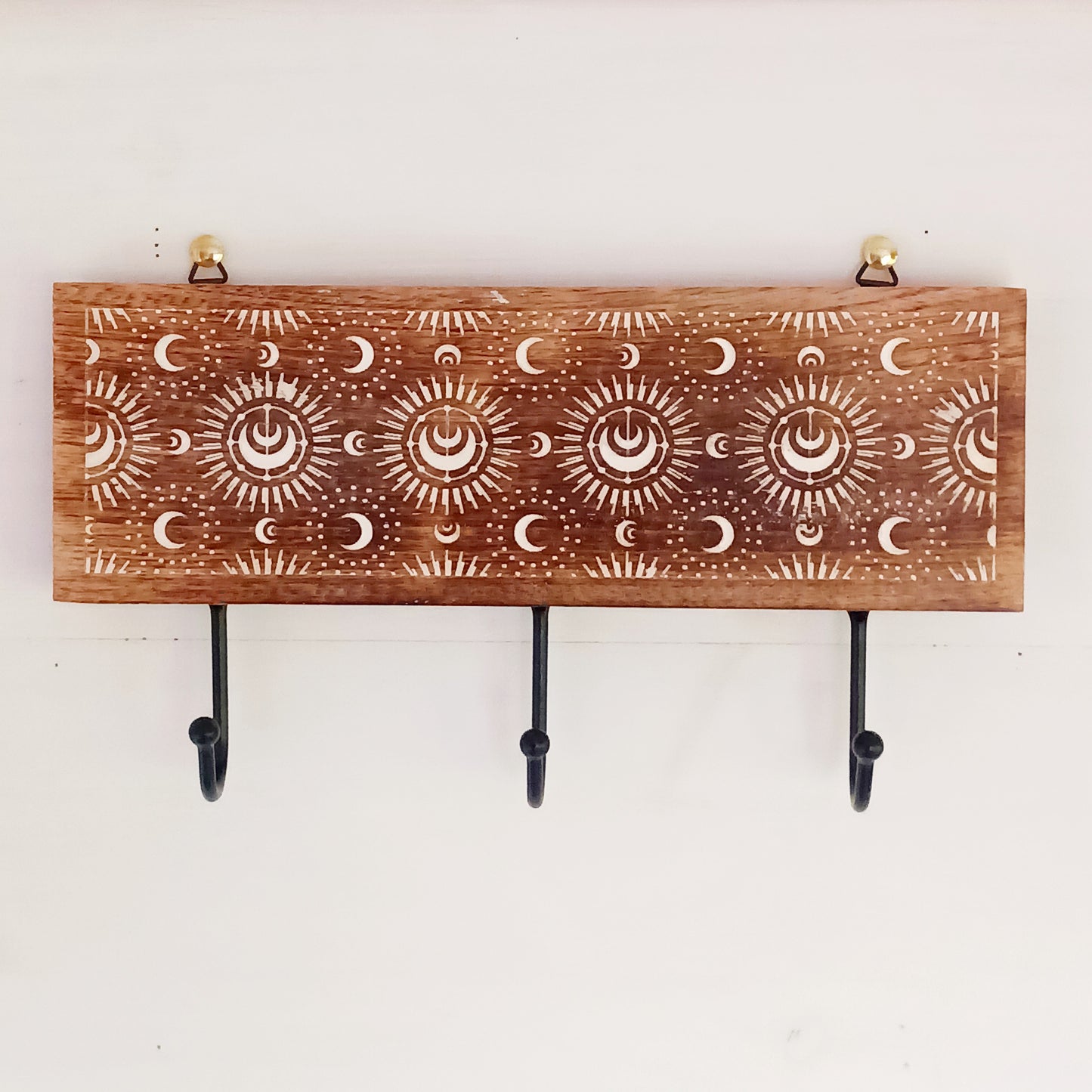 This wall mounted key hook or coat hanger has been hand carved from mango wood and decorated with crescent moons design, etched and painted white with 3 hooks for hanging. There are 2 hooks at the top on back from which to hang.