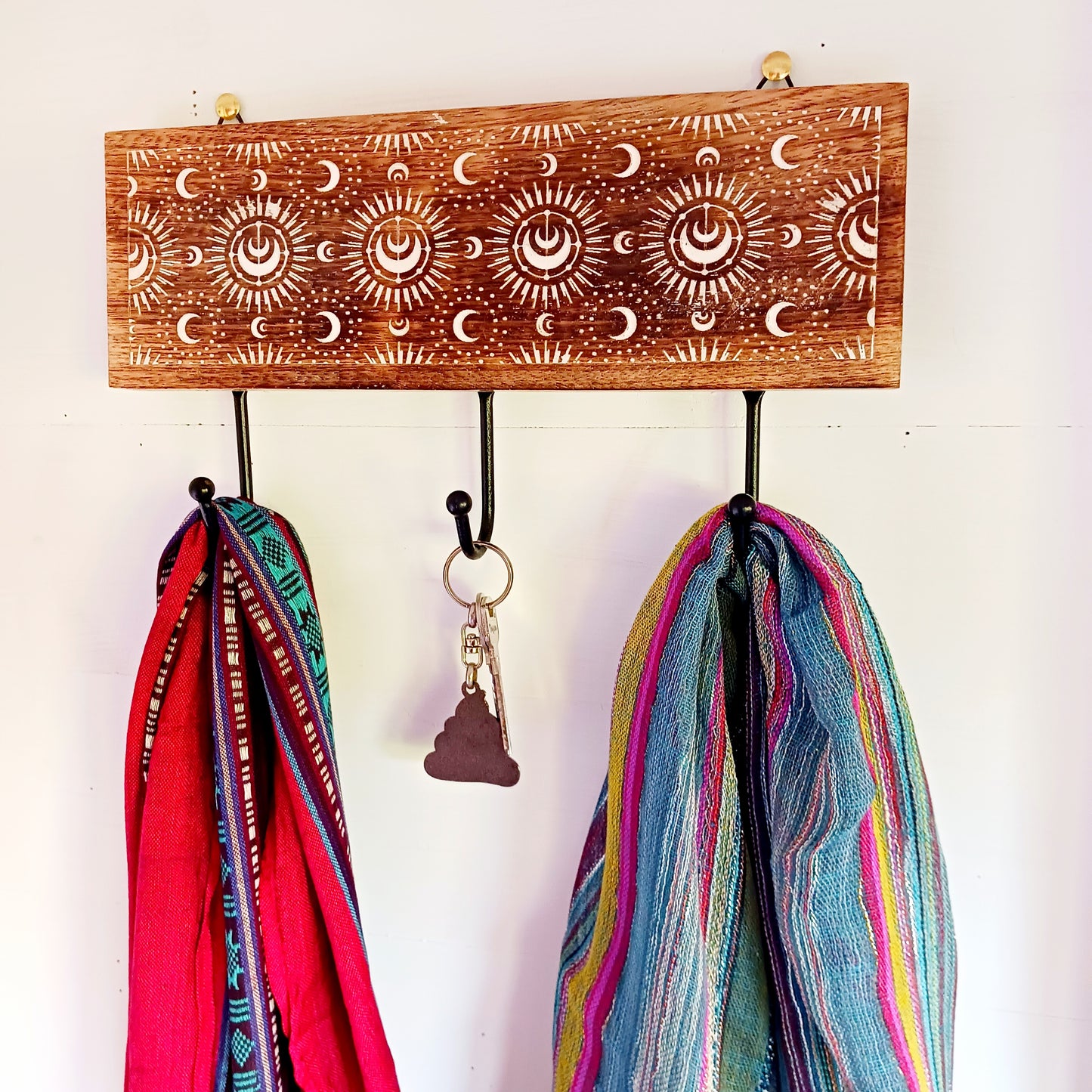 This wall mounted key hook or coat hanger has been hand carved from mango wood and decorated with crescent moons design, etched and painted white with 3 hooks for hanging. There are 2 hooks at the top on back from which to hang.