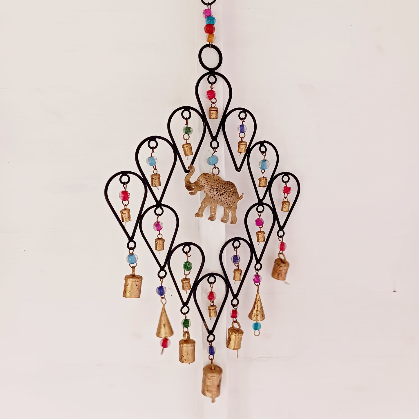 This beautiful windchime has been handmade in Northern India from recycled iron, utilising traditional iron-working skills. At the centre features an elephant image depicted with an upturned trunk, this is widely considered a symbol of good luck. The windchime is also decorated with Indian bells and colourful glass beads. The bells make a lovely, musical sound in a gentle breeze.