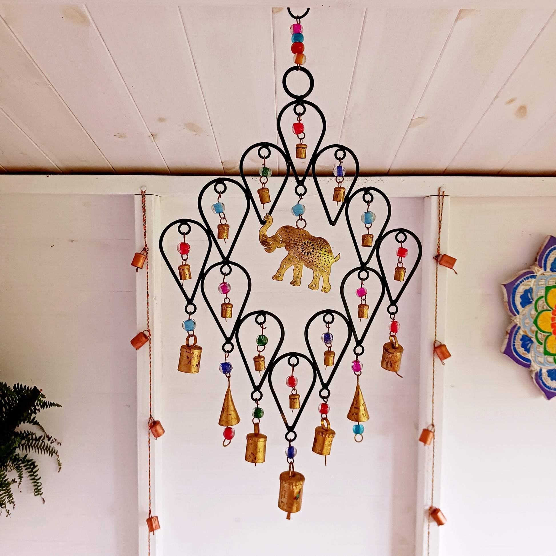 This beautiful windchime has been handmade in Northern India from recycled iron, utilising traditional iron-working skills. At the centre features an elephant image depicted with an upturned trunk, this is widely considered a symbol of good luck. The windchime is also decorated with Indian bells and colourful glass beads. The bells make a lovely, musical sound in a gentle breeze.