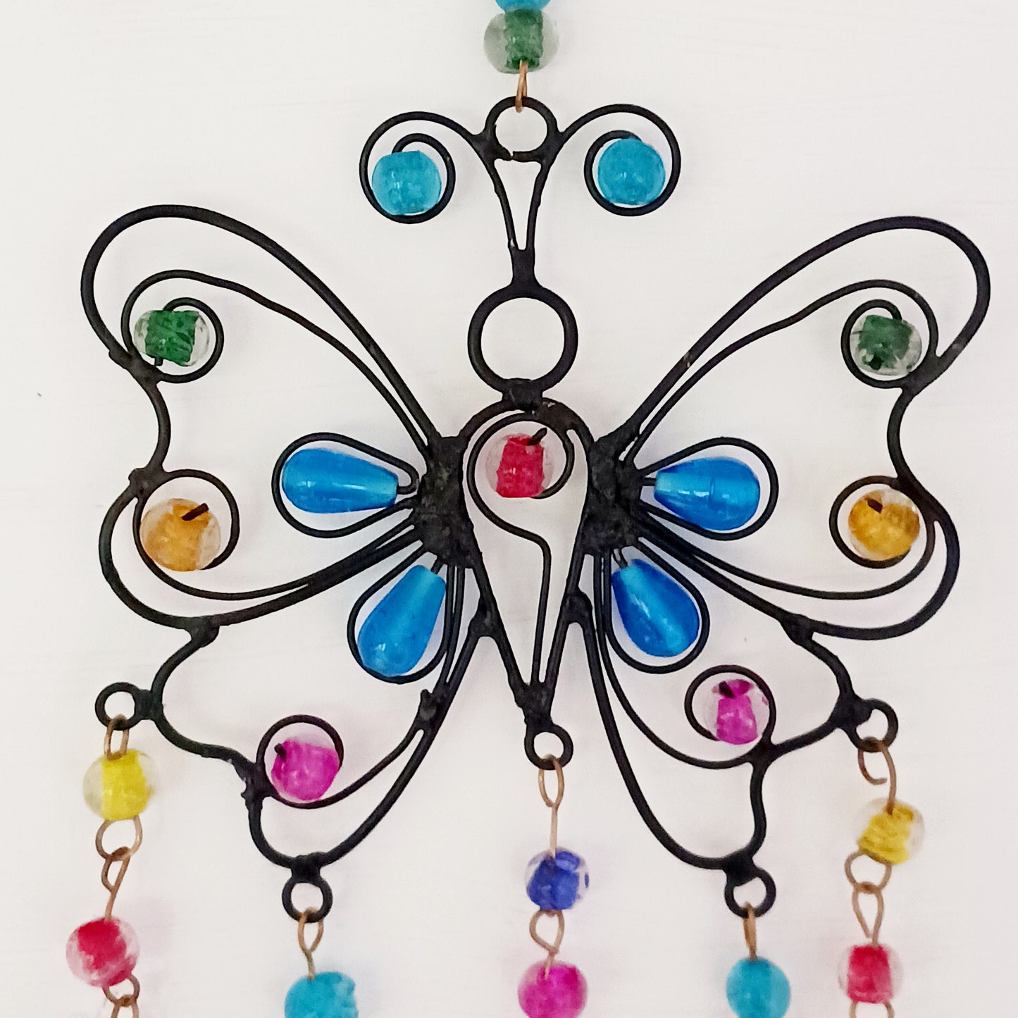 This pretty Butterfly windchime is decorated with vibrant mixed beads and Indian bells. Handmade from recycled iron, the bells make a lovely light tinking sound in a gentle breeze. Ideal for both inside the home or in your garden.