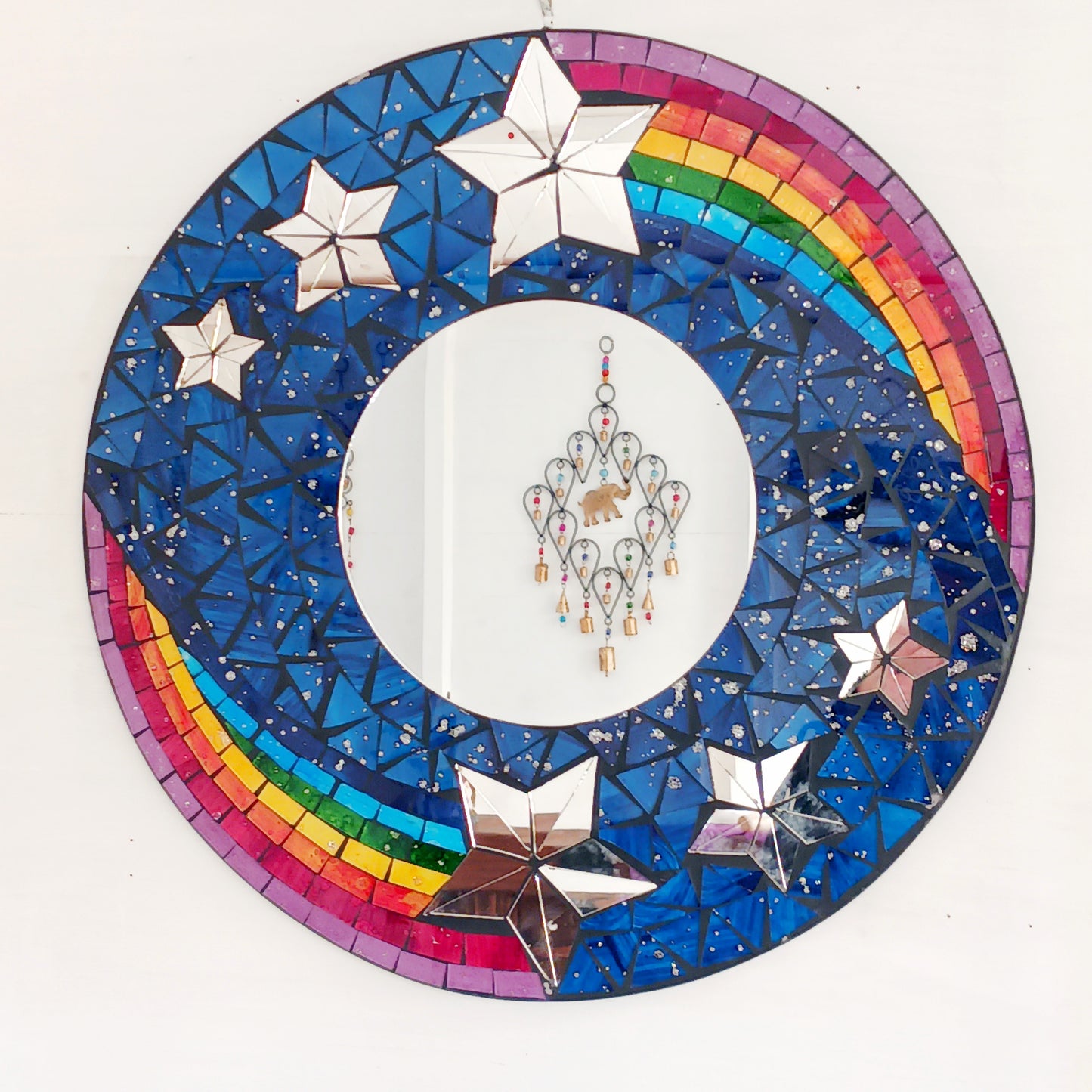 This bright and decorative round mirror is adorned with colourful mosaics creating a wonderful design of rainbow shooting stars flying through the night sky. 