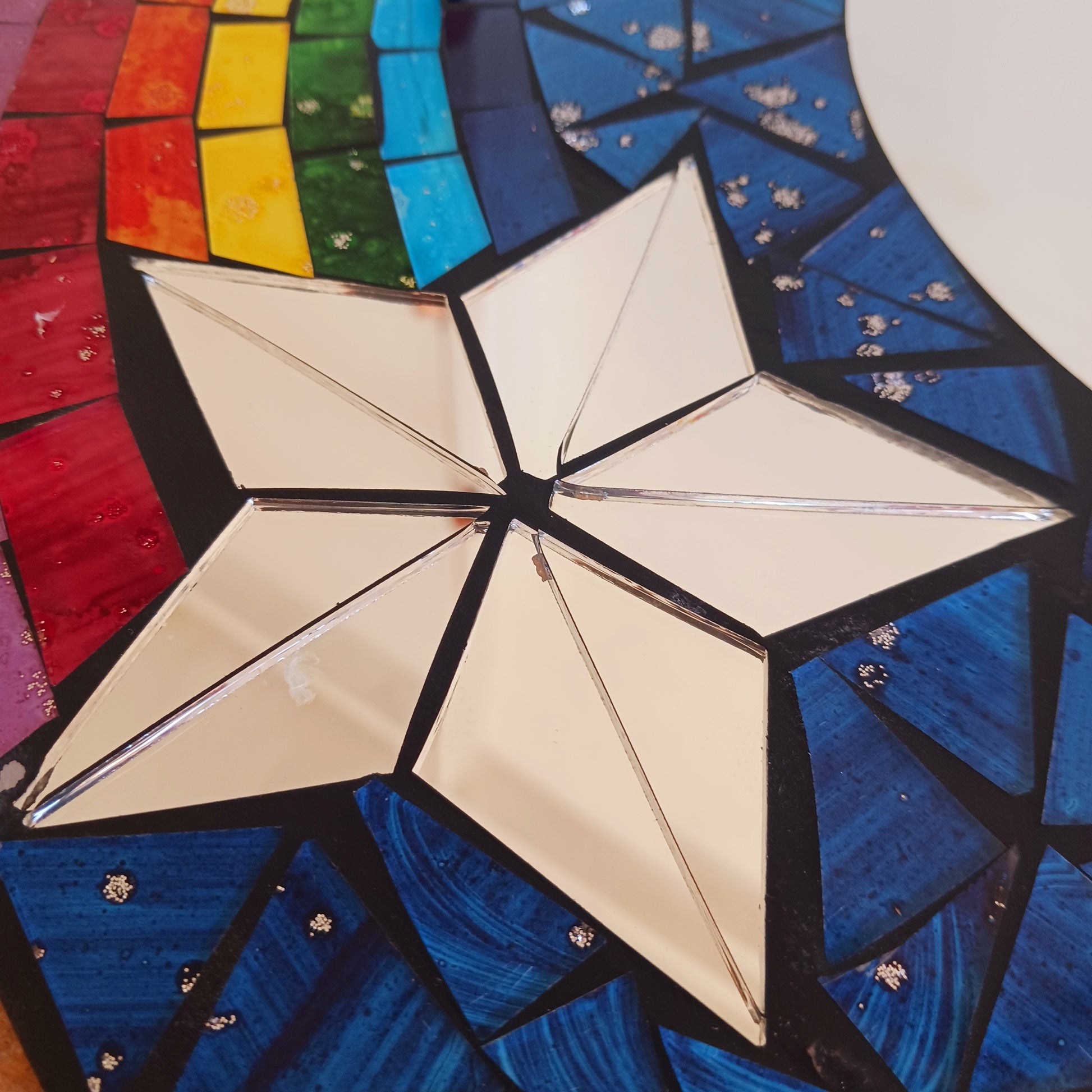 This bright and decorative round mirror is adorned with colourful mosaics creating a wonderful design of rainbow shooting stars flying through the night sky. 