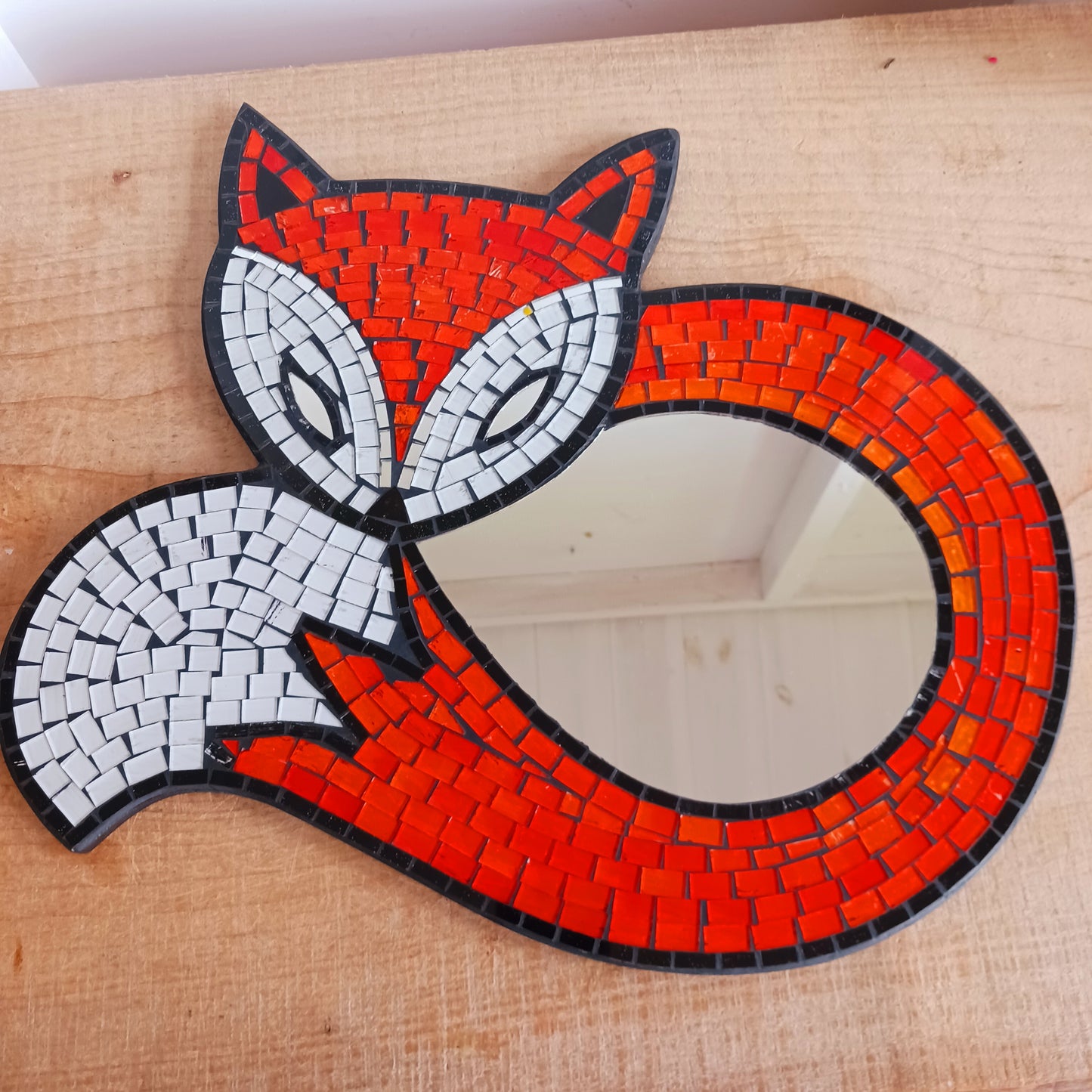 This lovely curled fox mirror has been handmade using small pieces of coloured glass to create a beautiful mosaic piece. There is an easy hanger on the back. Perfect for displaying on any wall in your home.