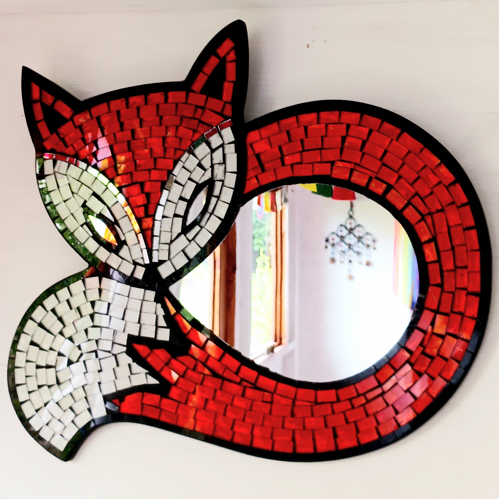 This lovely curled fox mirror has been handmade using small pieces of coloured glass to create a beautiful mosaic piece. There is an easy hanger on the back. Perfect for displaying on any wall in your home.