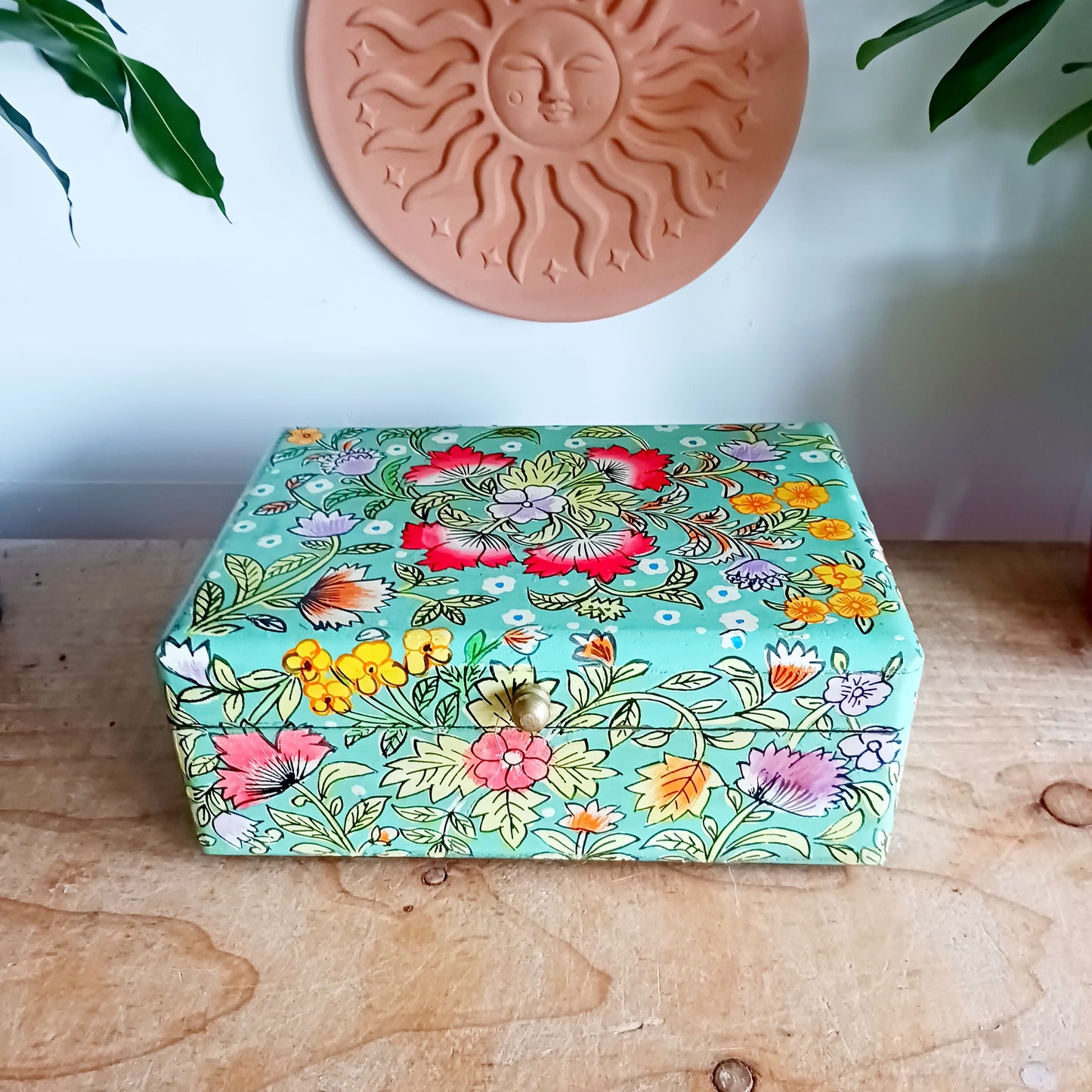 The Saanvi Handcrafted Small Wooden Box is a sustainable gift of beauty, designed to bring charm and practicality to any space. Expertly hand-painted in a bright mixed floral pattern on a pale blue background, this decorative box exudes artisanal elegance.