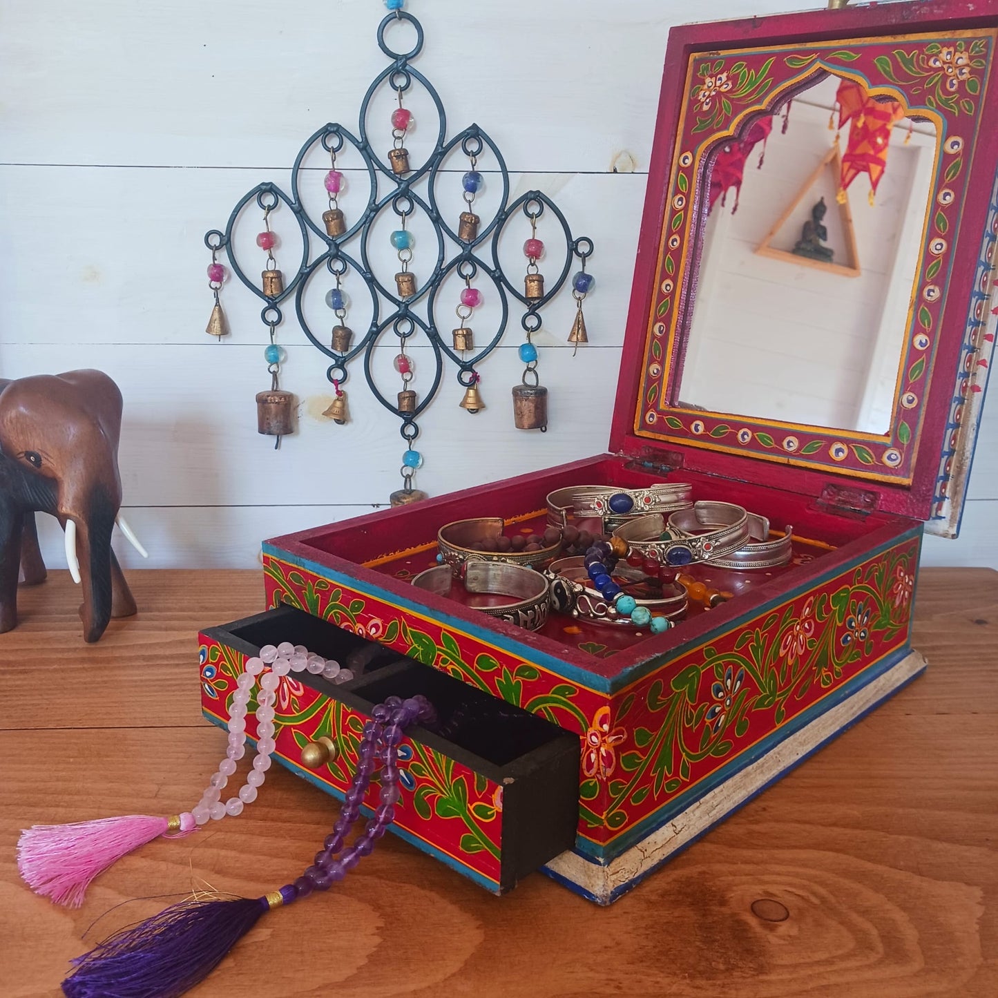 A beautiful peacock design, hand painted jewellery box in a palette of regal reds and blues made from sustainable mango wood.  This lovely box comprises a top opening section with mirror, and a single drawer; two useful compartments, accessed with discreet round knobs.