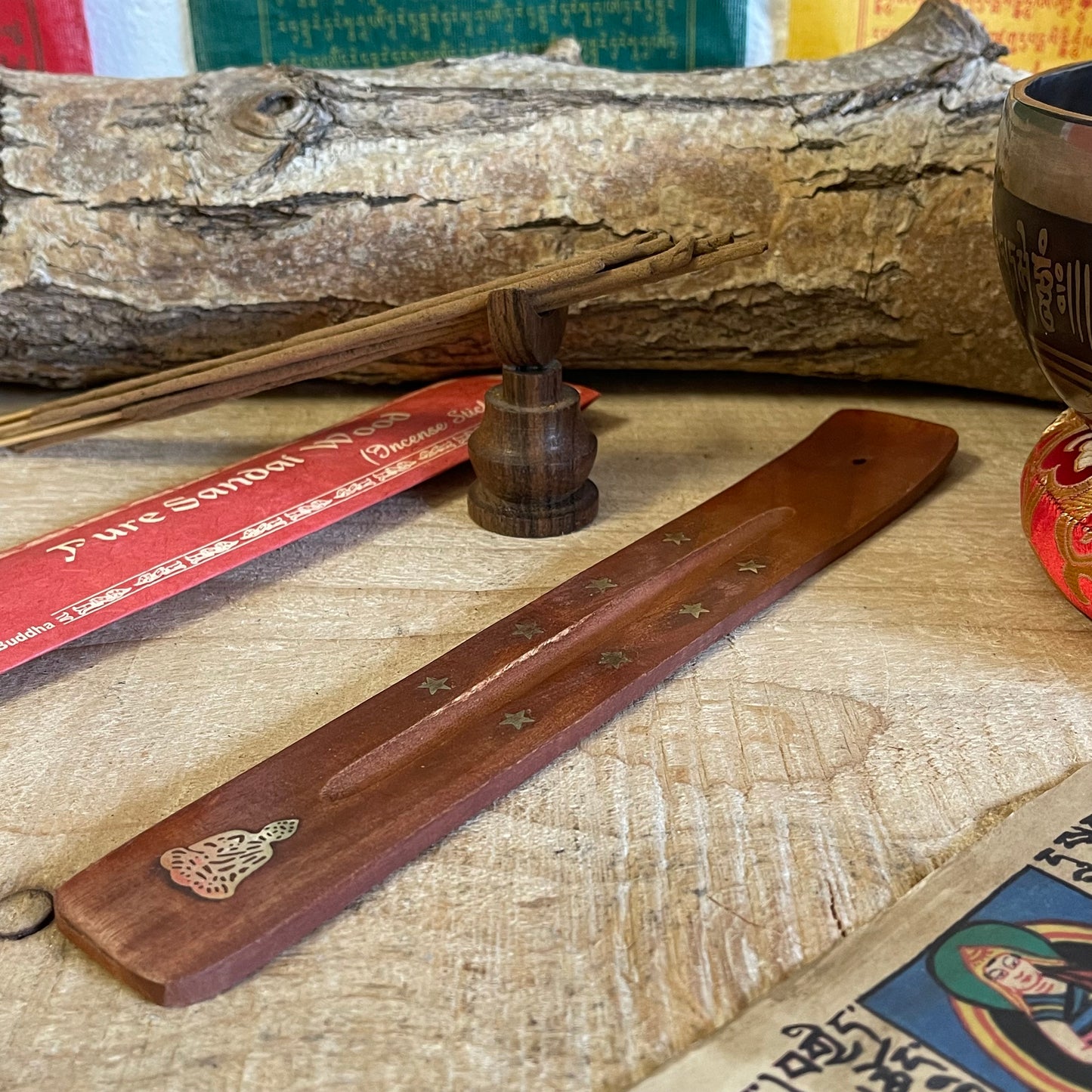 This top-rated shoehorn-style incense holder combines functionality with spiritual elegance. Made from high-quality mango wood, this ash catcher is adorned with brass inlays of stars and a serene Buddha figure, perfect for creating a peaceful ambiance. The long, gently curved shape securely holds incense sticks while collecting ash neatly along the wooden body, keeping your space clean and organized.