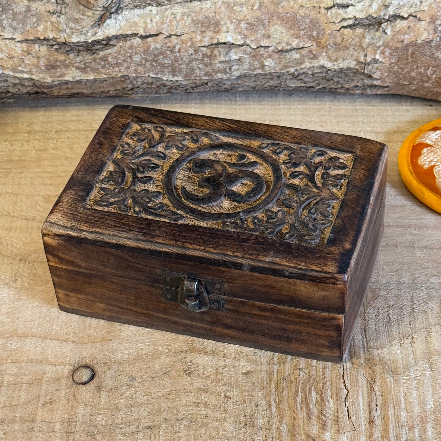 A lovely little hand carved Mango wood wooden box Hand carved in India It has a little brass fastening at the front, perfect for keeping your trinkets and keepsakes safe. Discover the beauty of hand carved craftsmanship from India with our Square Wooden Keepsake Box Om. Each box is carefully made from mango wood and features a charming brass fastening at the front. Keep your precious trinkets and keepsakes safe in this sturdy and stylish box.

Size is approx. 15 x 10 x 6 cm

Handmade in India