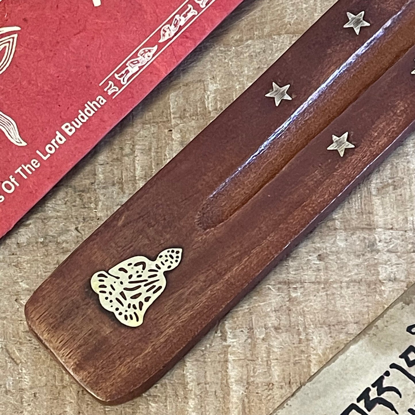 This top-rated shoehorn-style incense holder combines functionality with spiritual elegance. Made from high-quality mango wood, this ash catcher is adorned with brass inlays of stars and a serene Buddha figure, perfect for creating a peaceful ambiance. The long, gently curved shape securely holds incense sticks while collecting ash neatly along the wooden body, keeping your space clean and organized.