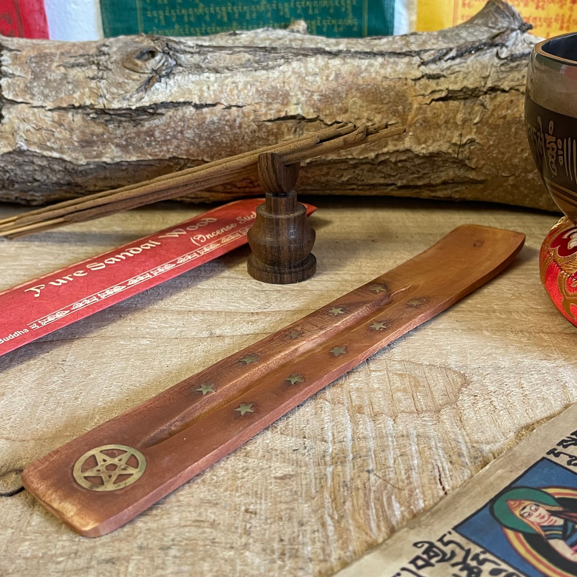 This popular shoehorn-style incense holder combines functionality with a mystical aesthetic, crafted from durable mango wood. The ash catcher features brass inlays of stars and a pentacle, symbolizing protection and balance, making it perfect for those who value spiritual symbolism. Its gently curved design securely holds incense sticks, while the wooden body catches ash as it falls, keeping your surfaces clean.