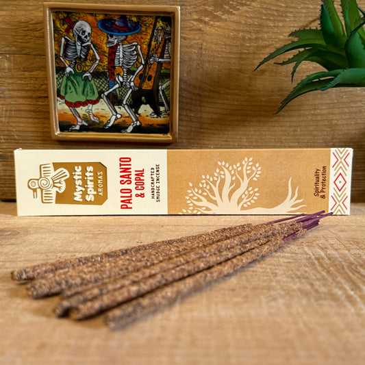 Step into the sacred fires of purification with Mystic Spirits Palo Santo and Copal Smudge Sticks. Hand-rolled in India from a sacred blend of fragrant gums, resins, wood powders, herbs, and spices, these incense sticks carry the wisdom of the ancients.

Palo Santo, the revered “holy wood,” offers a gentle fragrance that is woody, subtly sweet, with whispers of citrus and mint. It is known among shamans for clearing negative energies, uplifting the spirit, and creating sacred space.