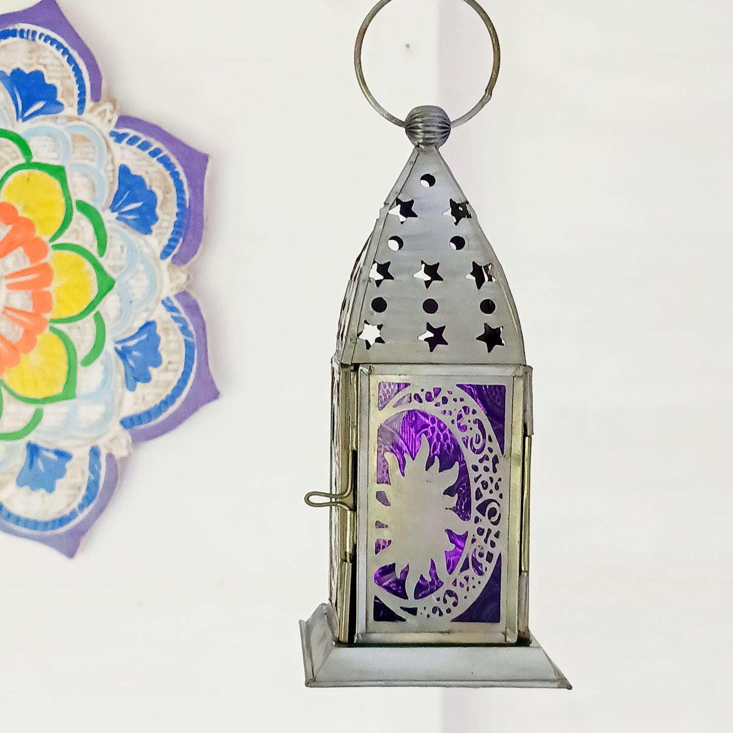 Bring warmth, colour and spiritual harmony to your home with this beautiful Moon & Stars Glass Lantern. Designed with vibrant coloured glass panels and a decorative metal cut-out canopy, this lantern creates a calming glow that enhances meditation spaces, yoga rooms and home décor.