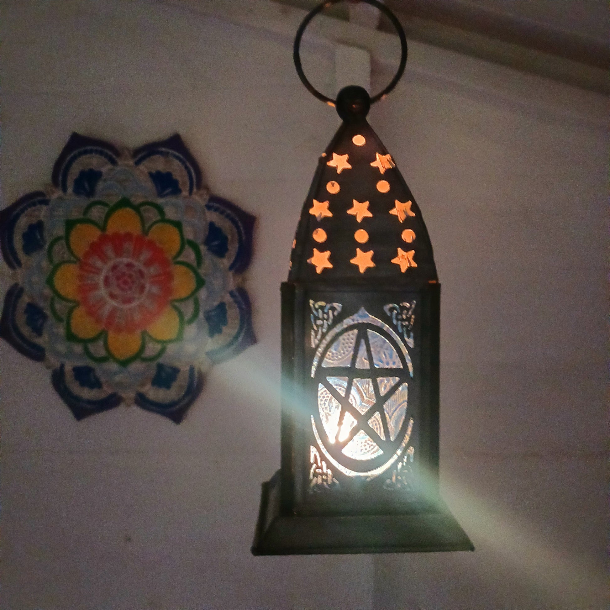 Bring warmth, colour and spiritual harmony to your home with this beautiful Pentagram Glass Lantern. Designed with vibrant coloured glass panels and a decorative metal cut-out canopy, this lantern creates a calming glow that enhances meditation spaces, yoga rooms and home décor.