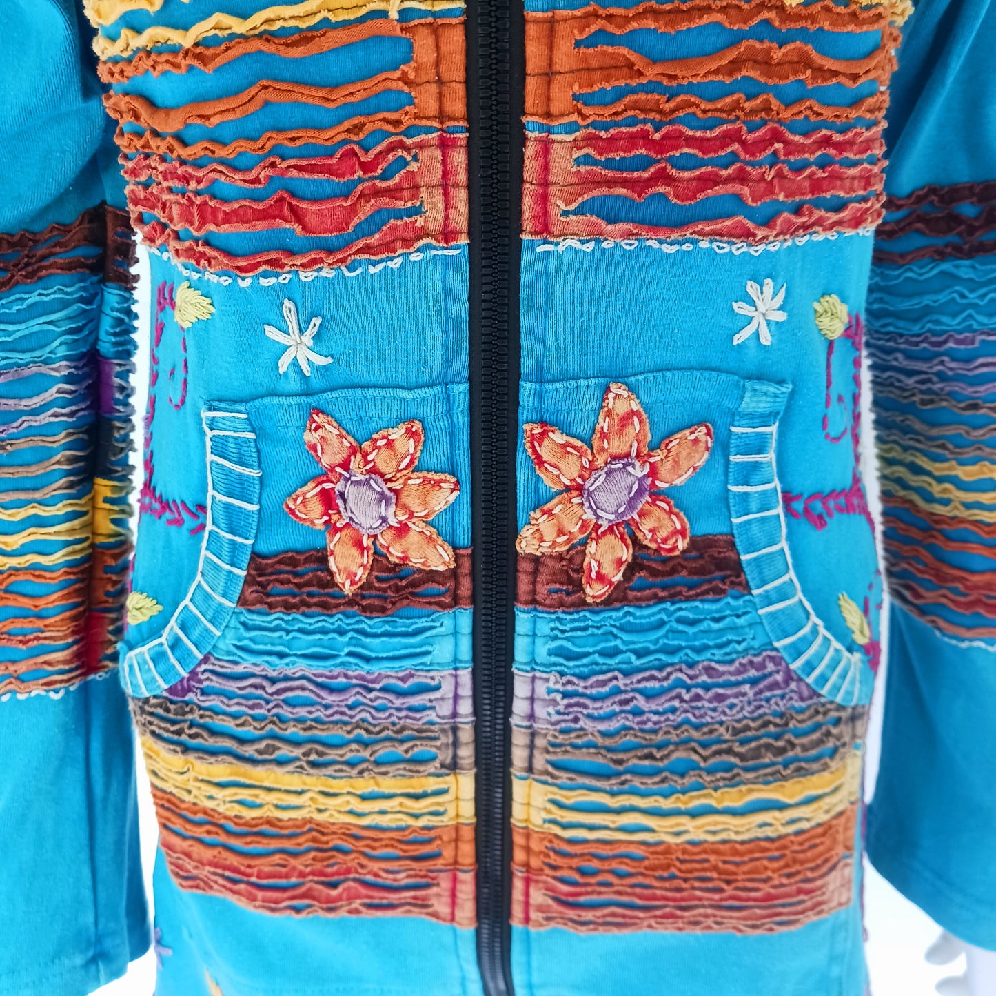 Make a bold statement with this handmade turquoise Pixie Jacket, a striking patchwork coat designed for free spirits and lovers of expressive, bohemian fashion. Crafted in Nepal from soft, stretchy cotton jersey, this longline jacket blends vibrant colours, artistic prints, and intricate detailing into a truly unique outerwear piece.