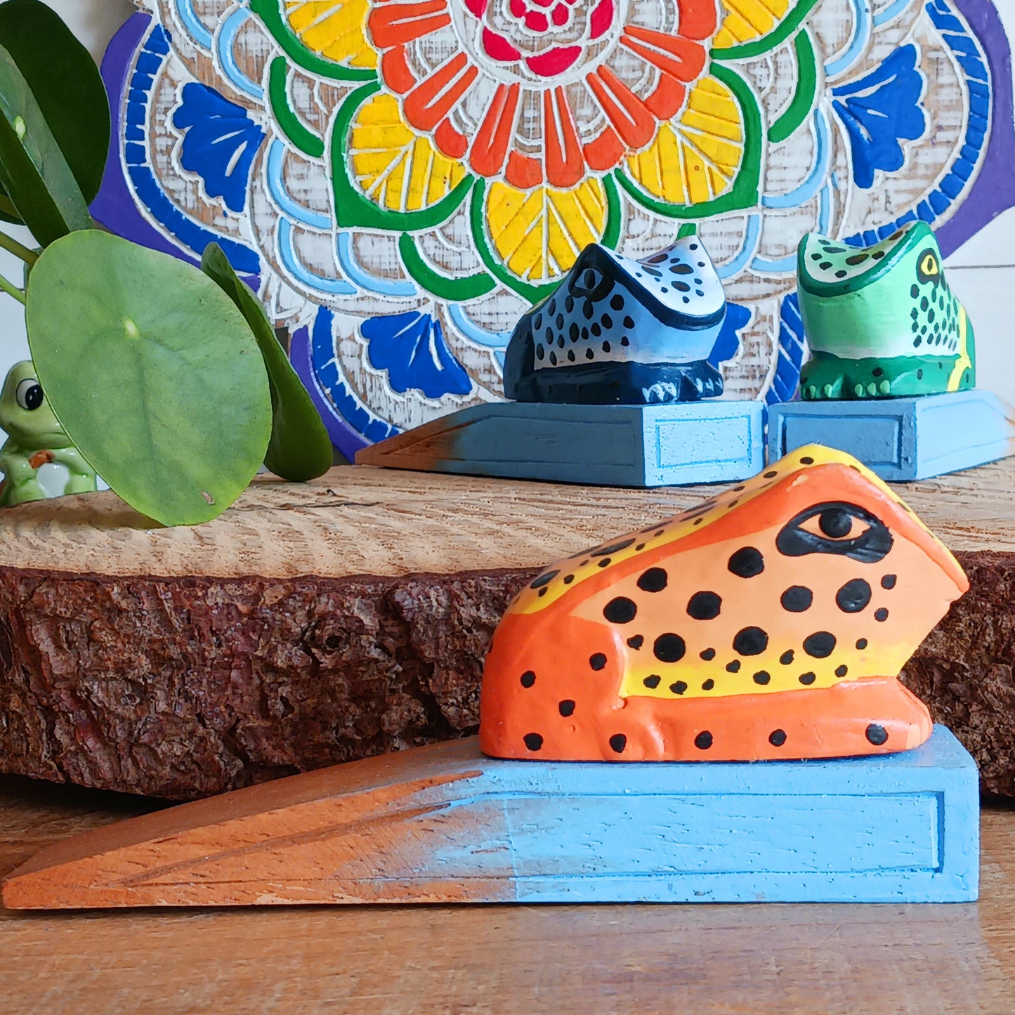 Bring charm and character into your home with this decorative wooden door stopper, featuring a turquoise base and a playful, hand-painted dotty frog design in vibrant blue, green, and orange. Perfect for propping open doors in style, this quirky wedge door stop is both practical and fun.