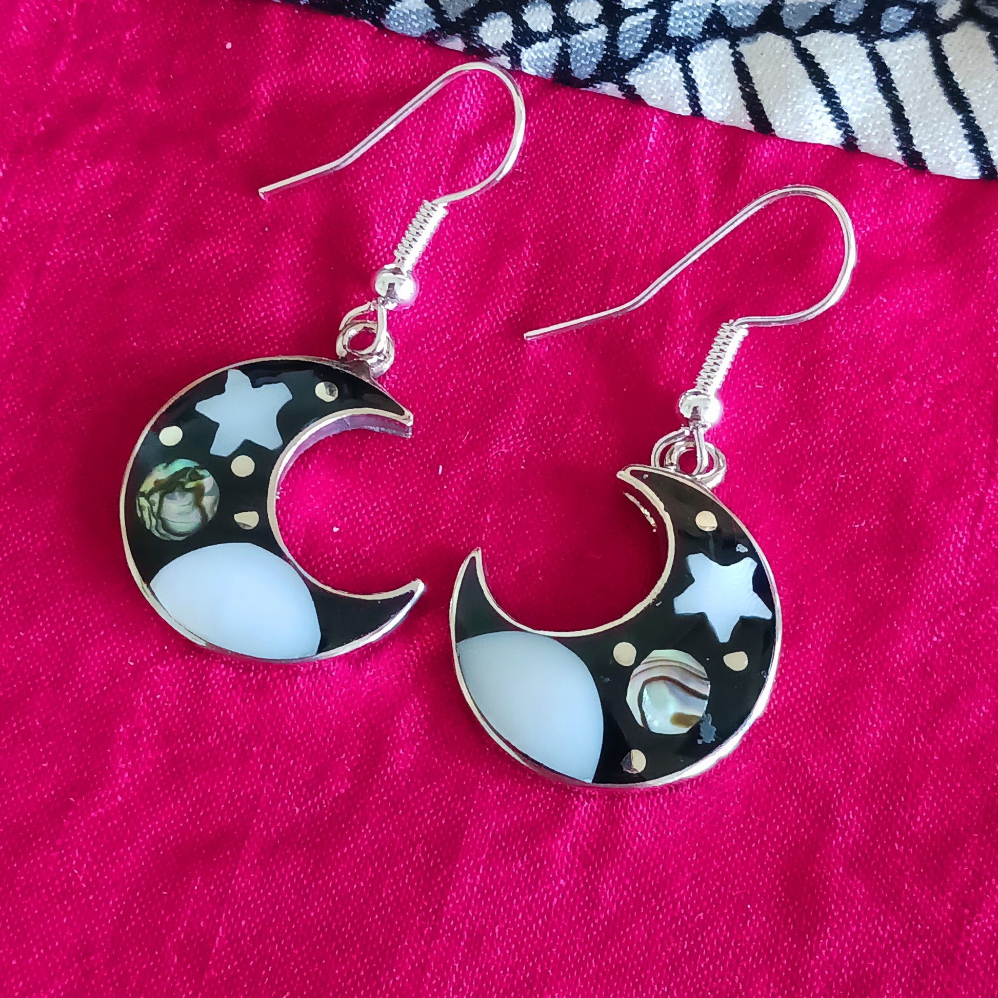 This set of beautiful celestial themed earrings are hand crafted in Taxco, Mexico. Utilising a eye-catching crescent moon design created using traditional Alpaca steel as the frame. These earrings have a celestial theme created using dyed, iridescent abalone shell.