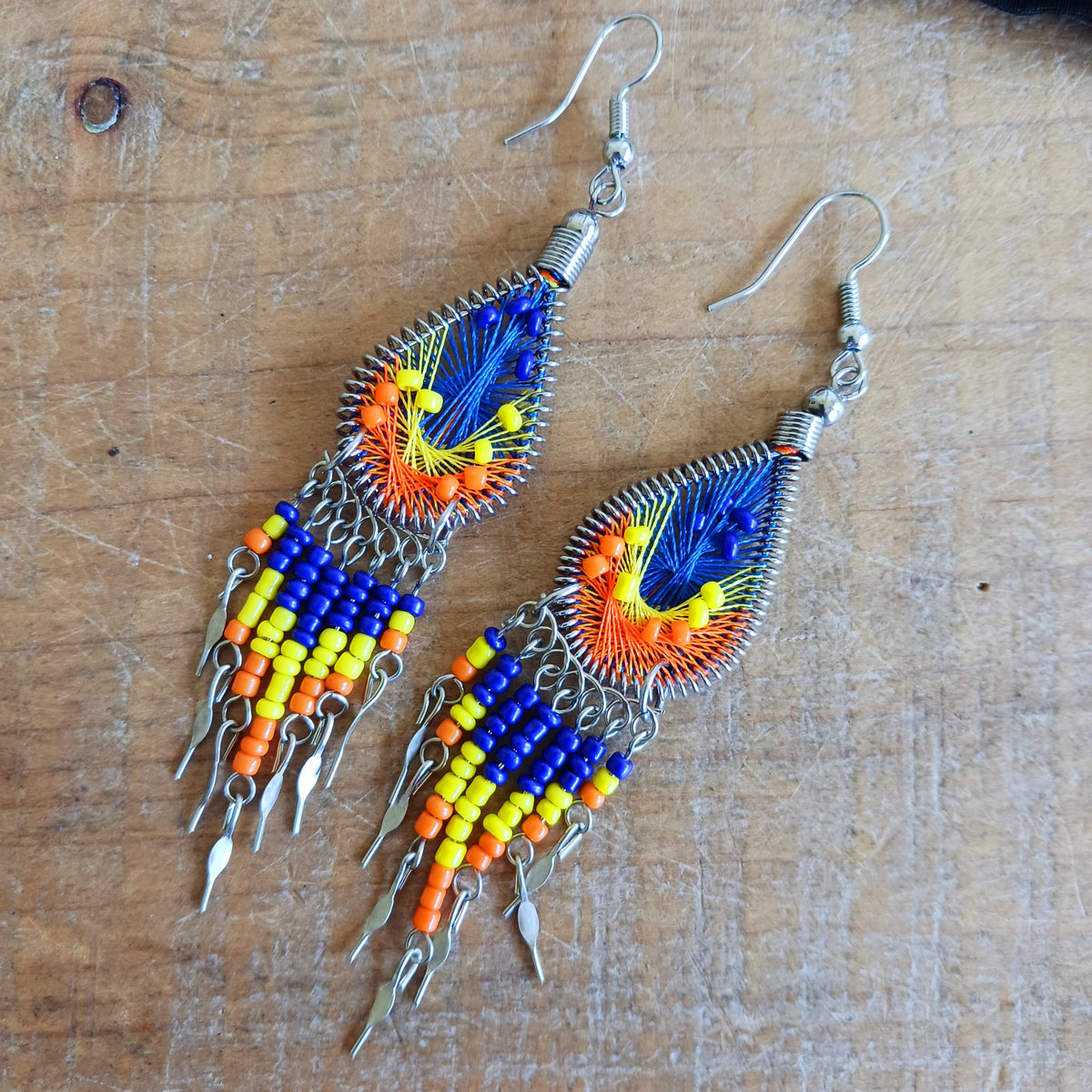Add a splash of colour to your look with these beautiful handmade Peruvian woven teardrop earrings. Inspired by the vibrant colours and patterns of a peacock feather, each earring features intricate woven detailing complemented by coordinating beads and delicate silver-tone embellishments.