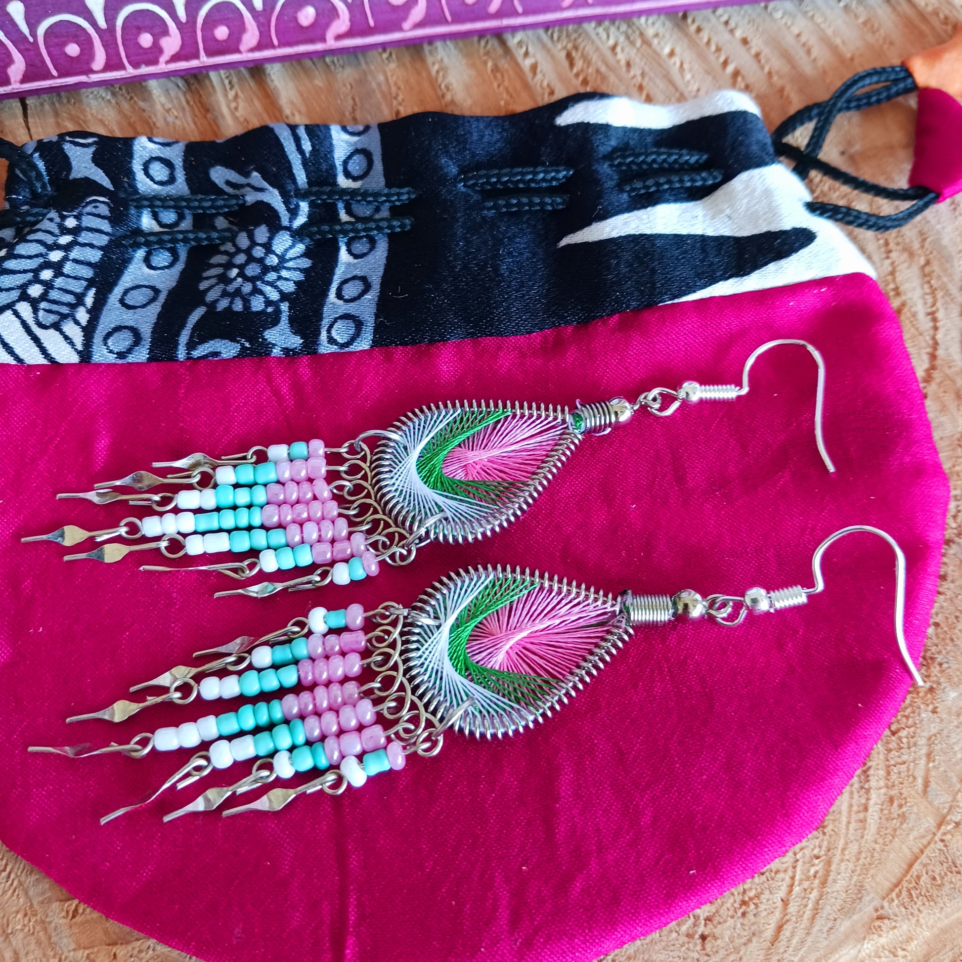 These beautiful and eye-catching earrings are handmade in Peru and feature an array of gorgeous colours. A woven teardrop, similar in style to a peacock feather, is finished with co-ordinating beads and silver embellishments. Ideal for a night out or for dressing up your boho look!