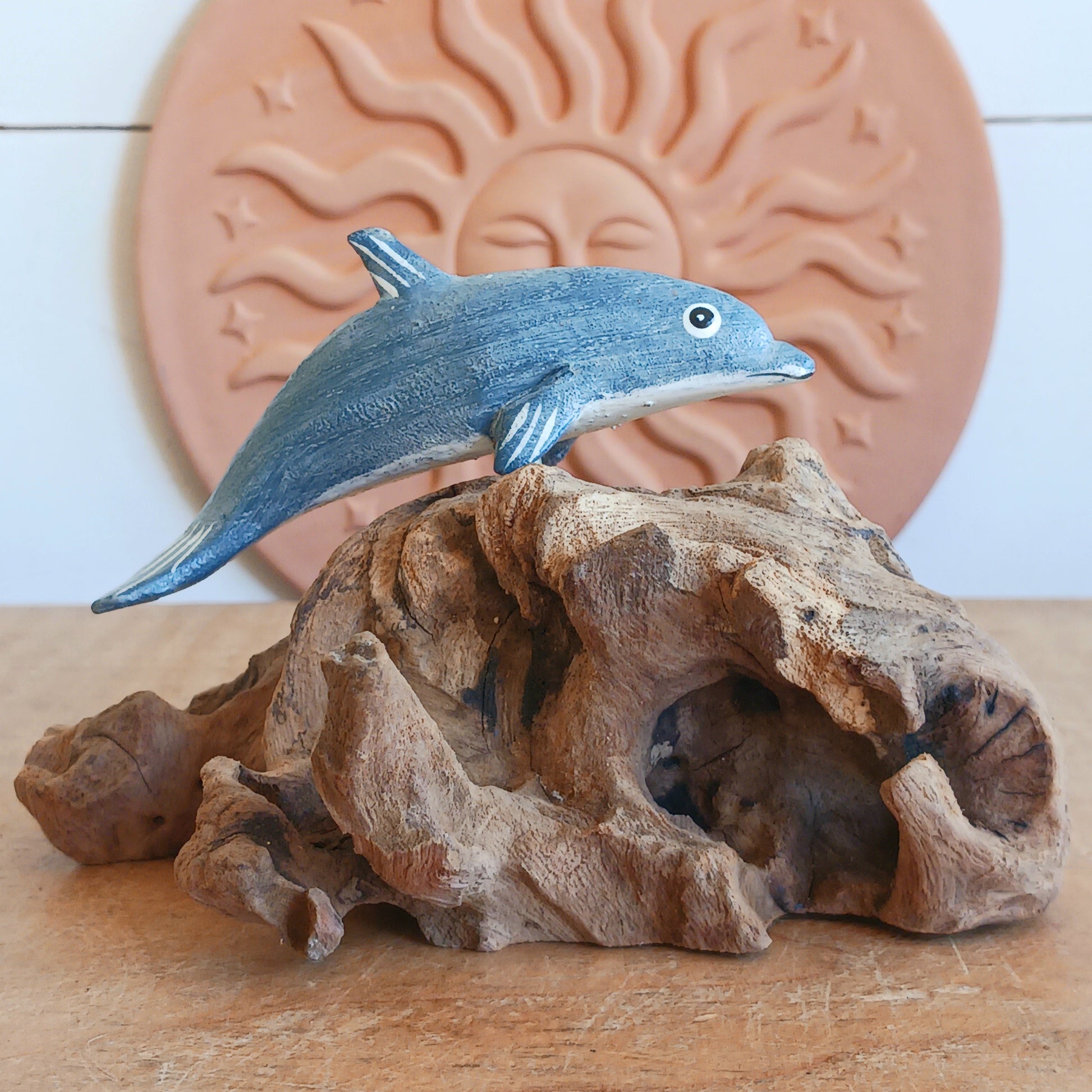 Bring the peaceful beauty of the ocean into your home with this Handcrafted Wooden Blue Dolphin Sculpture. Expertly crafted from sustainably sourced wood, this elegant decorative piece features a beautifully hand-painted blue dolphin gracefully mounted on natural driftwood, creating a striking coastal-inspired display.