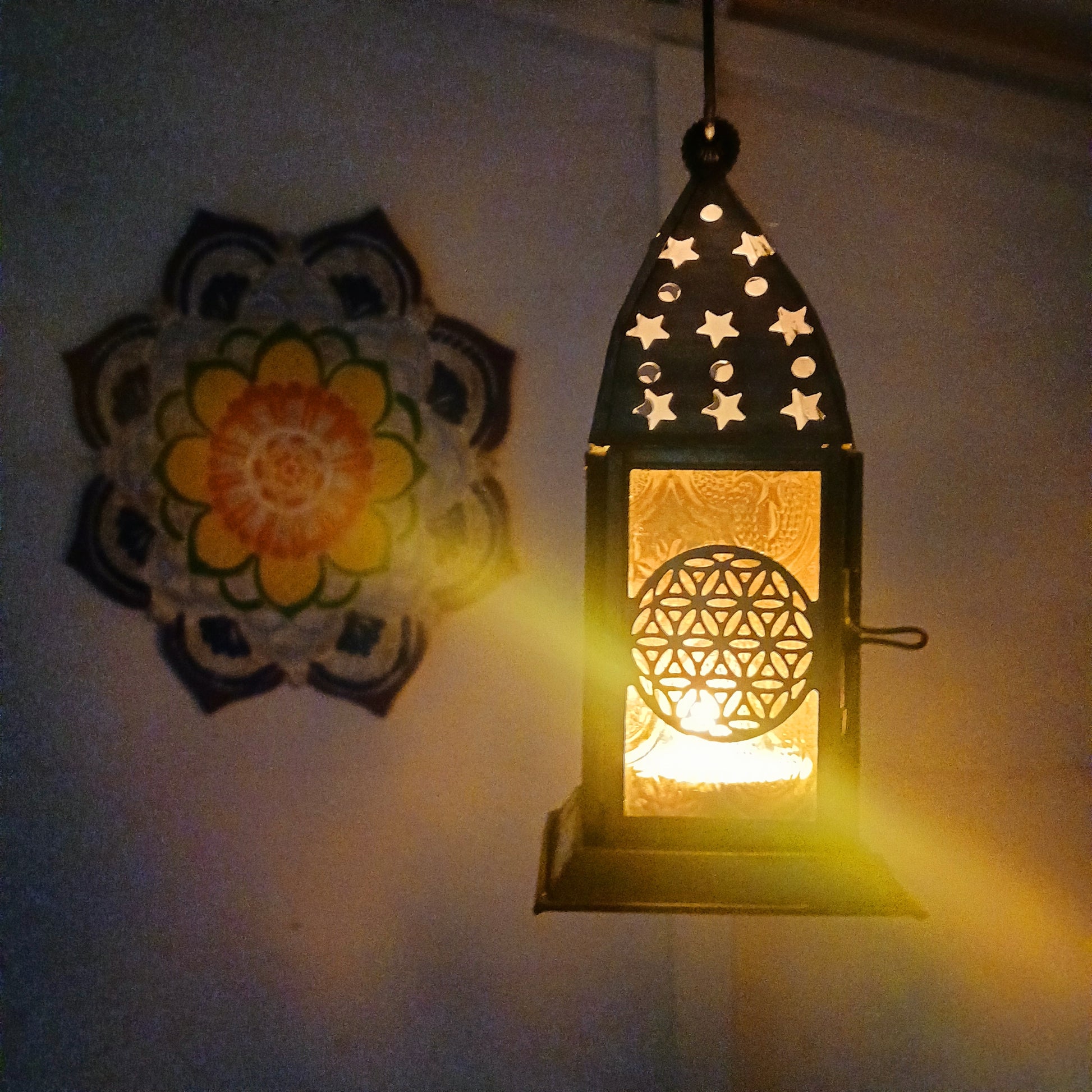 Bring warmth, colour and spiritual harmony to your home with this beautiful Flower of Life Glass Lantern. Designed with vibrant coloured glass panels and a decorative metal cut-out canopy, this lantern creates a calming glow that enhances meditation spaces, yoga rooms and home décor.