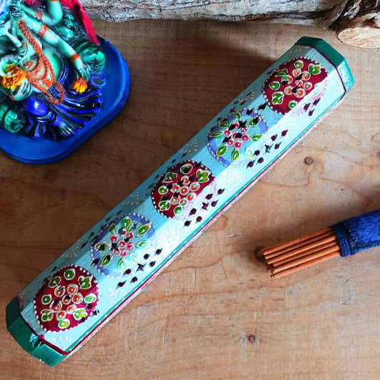 This beautiful turquoise wooden Incense box has been hand painted and has a curved hinged lid. It can accommodate both incense sticks and cones. There is also a place for you to safely store your incense sticks at the bottom on the box.