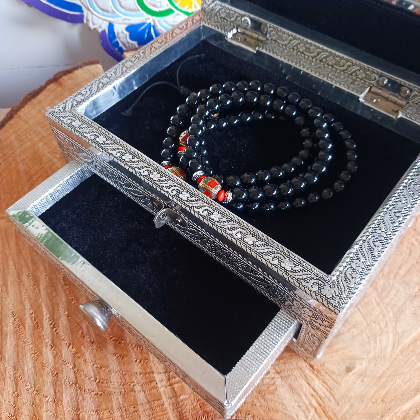 This beautiful silver colour embossed aluminium jewellery box has plenty of space for you to keep you jewellery and other valueables, and comes with a pull-out drawer.  It is lined with black cotton velvet and intricately decorated with a hamsa hand on the lid, and ornate bordering.