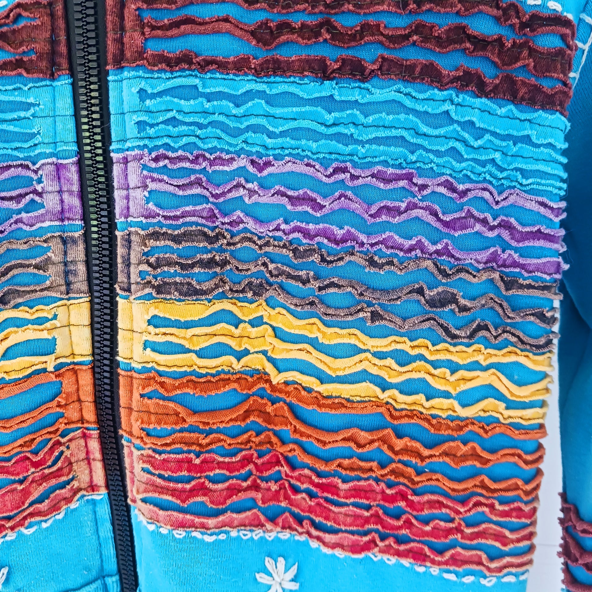 Make a bold statement with this handmade turquoise Pixie Jacket, a striking patchwork coat designed for free spirits and lovers of expressive, bohemian fashion. Crafted in Nepal from soft, stretchy cotton jersey, this longline jacket blends vibrant colours, artistic prints, and intricate detailing into a truly unique outerwear piece.