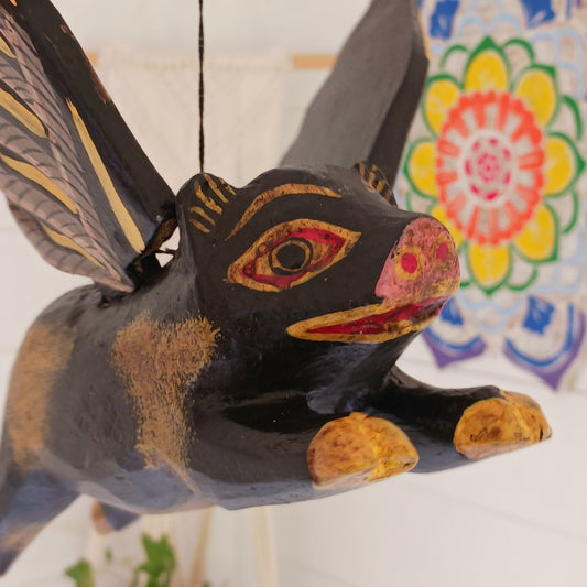 Invite protective energy and traditional charm into your home with this handcrafted Flying Pig Spirit Guardian from Bali. Known locally as a "Cradle Guardian," this winged figure is believed to ward off negative entities and is often placed in temples or homes, suspended from elevated areas like doorways or windows. Its downward-facing posture channels protection, while the strong twine loop allows for easy hanging. 