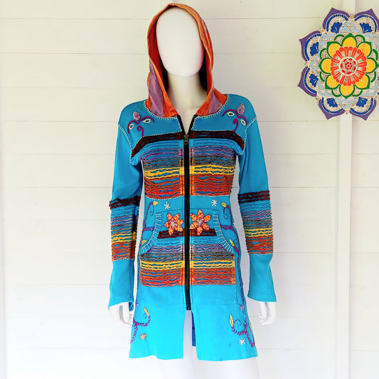 Make a bold statement with this handmade turquoise Pixie Jacket, a striking patchwork coat designed for free spirits and lovers of expressive, bohemian fashion. Crafted in Nepal from soft, stretchy cotton jersey, this longline jacket blends vibrant colours, artistic prints, and intricate detailing into a truly unique outerwear piece.