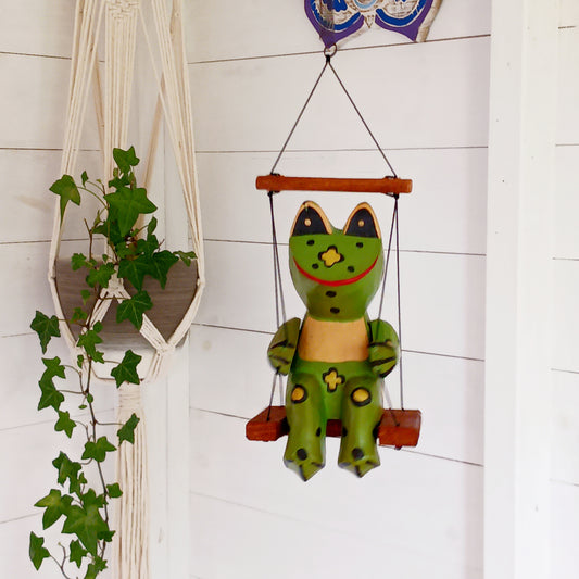 Add charm and whimsy to any space with this adorable hand-carved wooden frog! Perched on a swing and suspended by a long spring, this frog bounces gently in the air, bringing playful motion and joy to any room. Each piece is carefully hand-painted and carved from fast-growing, sustainably harvested albesia wood, making it a more eco-friendly choice for softwood décor. Whether for a nursery, porch, or creative space, this eye-catching novelty is sure to delight kids and adults alike!