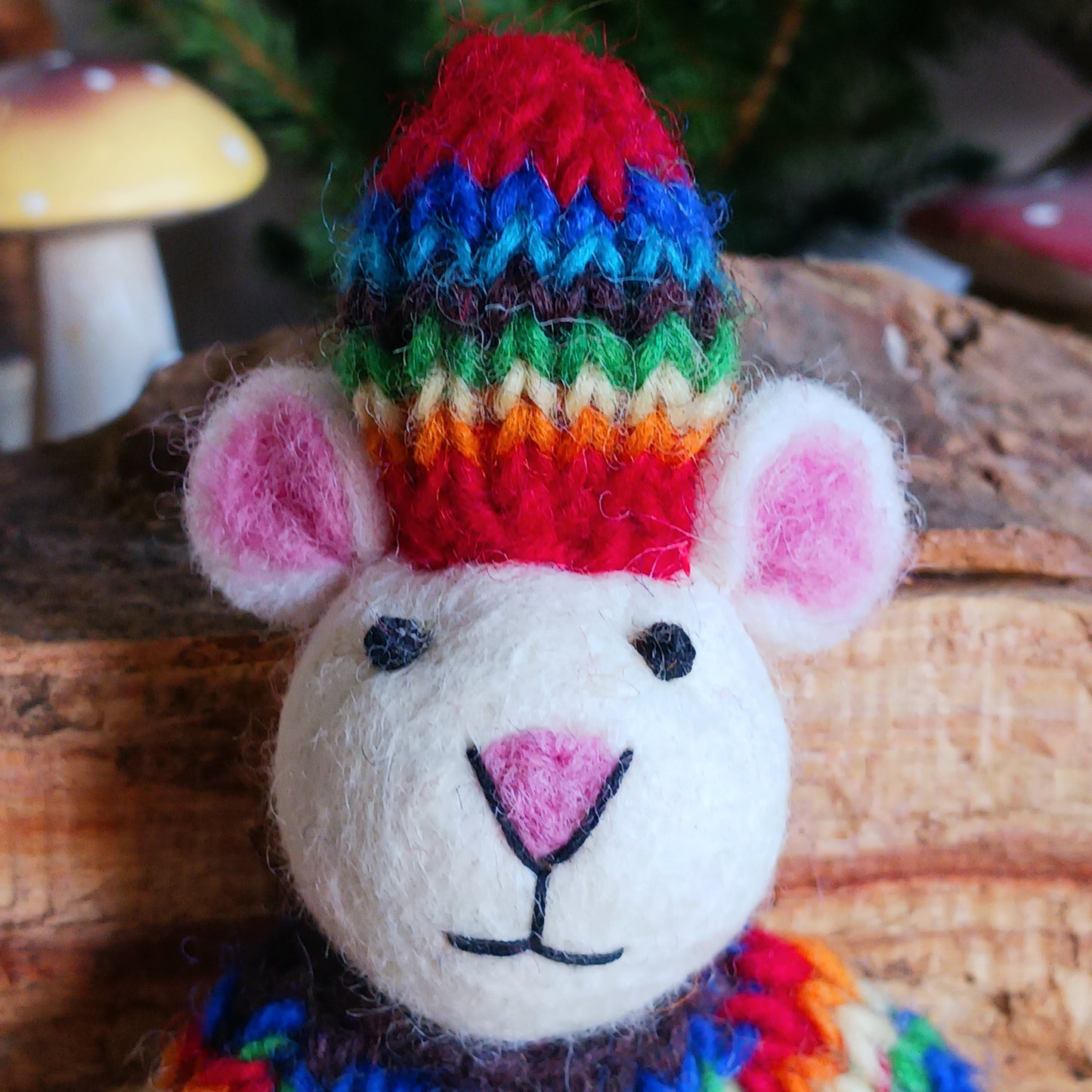 Bring instant festive cheer to your home with this adorable Christmas Tree Mouse Decoration. Dressed in a hand-knitted rainbow jumper and matching hat, this charming little mouse captures the magic of the season at first sight. Its sweet pink nose, expressive eyes, and cartoon-like ears bring out the childlike joy in anyone who sees it.