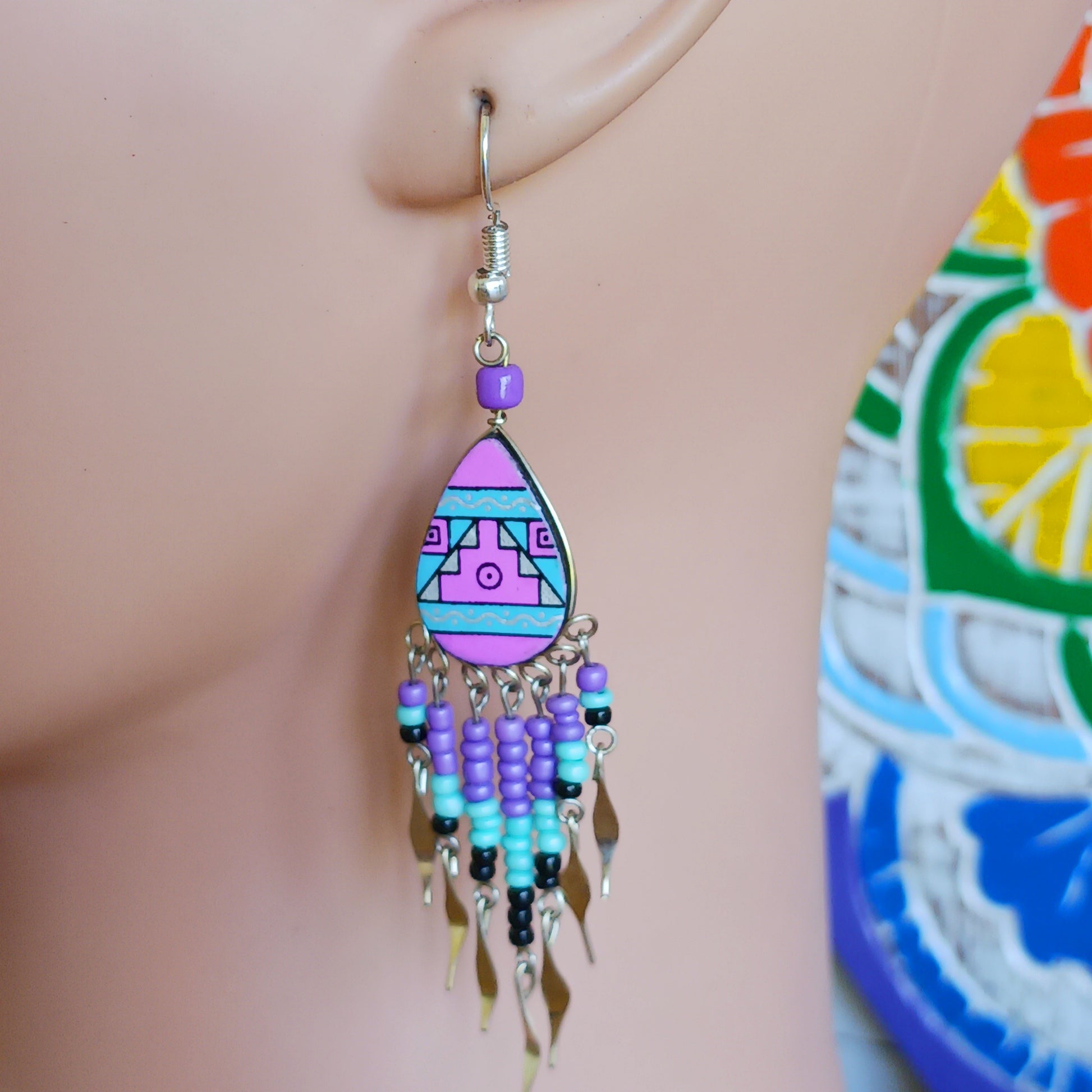 These beautiful and eye-catching earrings are handmade in Peru and feature traditional Incan patterns on the front, the back is coloured black. They are shaped in a teardrop style and are finished with coloured coordinating beads, silver embellishments and silver-plated hooks.