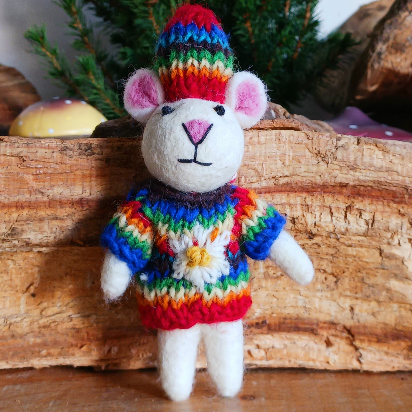 Bring instant festive cheer to your home with this adorable Christmas Tree Mouse Decoration. Dressed in a hand-knitted rainbow jumper and matching hat, this charming little mouse captures the magic of the season at first sight. Its sweet pink nose, expressive eyes, and cartoon-like ears bring out the childlike joy in anyone who sees it.