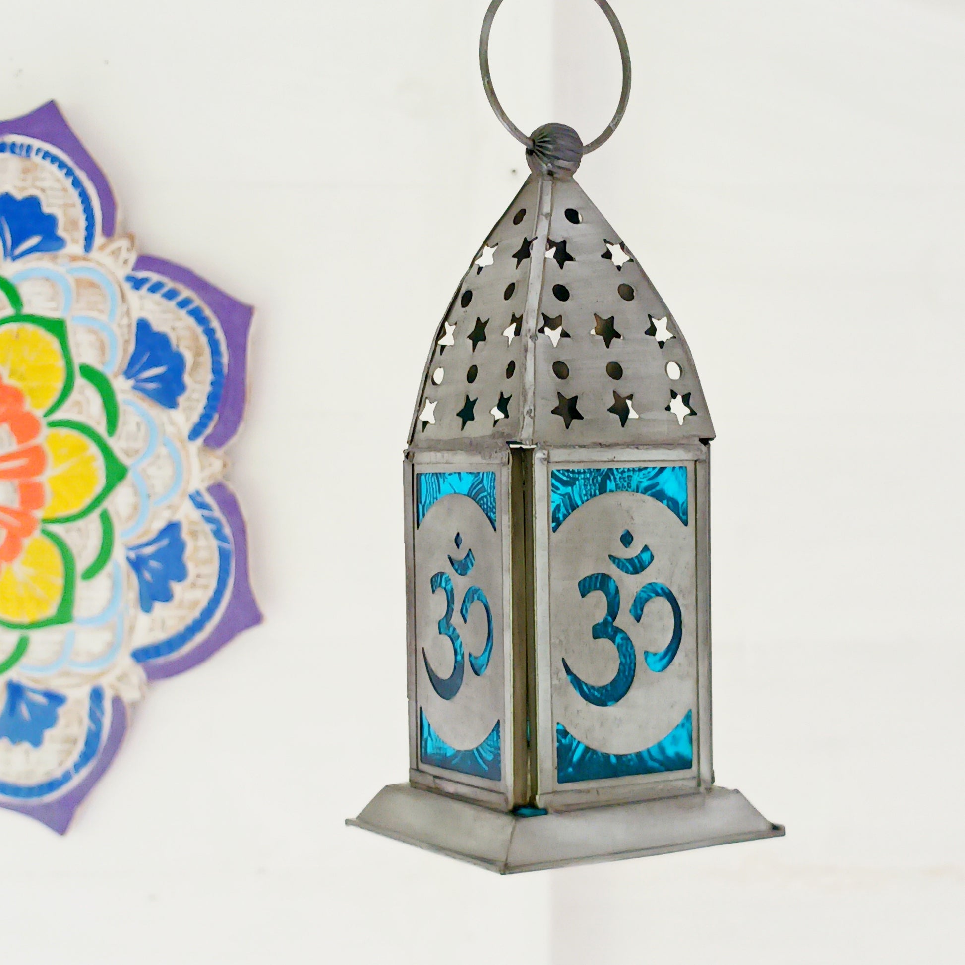Bring warmth, colour and spiritual harmony to your home with this beautiful Om Symbol Glass Lantern. Designed with vibrant coloured glass panels and a decorative metal cut-out canopy, this lantern creates a calming glow that enhances meditation spaces, yoga rooms and home décor.