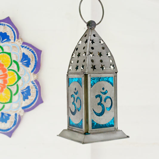 Bring warmth, colour and spiritual harmony to your home with this beautiful Om Symbol Glass Lantern. Designed with vibrant coloured glass panels and a decorative metal cut-out canopy, this lantern creates a calming glow that enhances meditation spaces, yoga rooms and home décor.