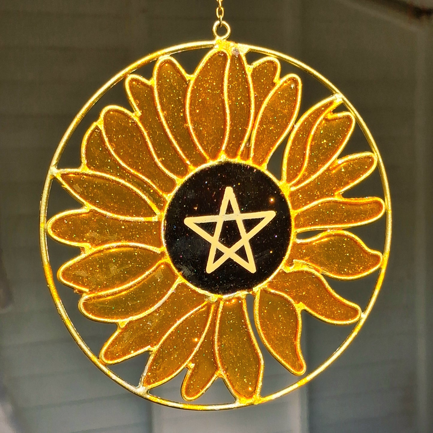 Add a touch of sunshine to the home with this Summer Solstice sunflower suncatcher. This charming suncatcher is inspired by the Summer Solstice, featuring a beautifully detailed sunflower, pentagram, star and crescent moon design made from metal and resin. Hang it in the window to catch the light and bring a cheerful, colourful glow to any room.