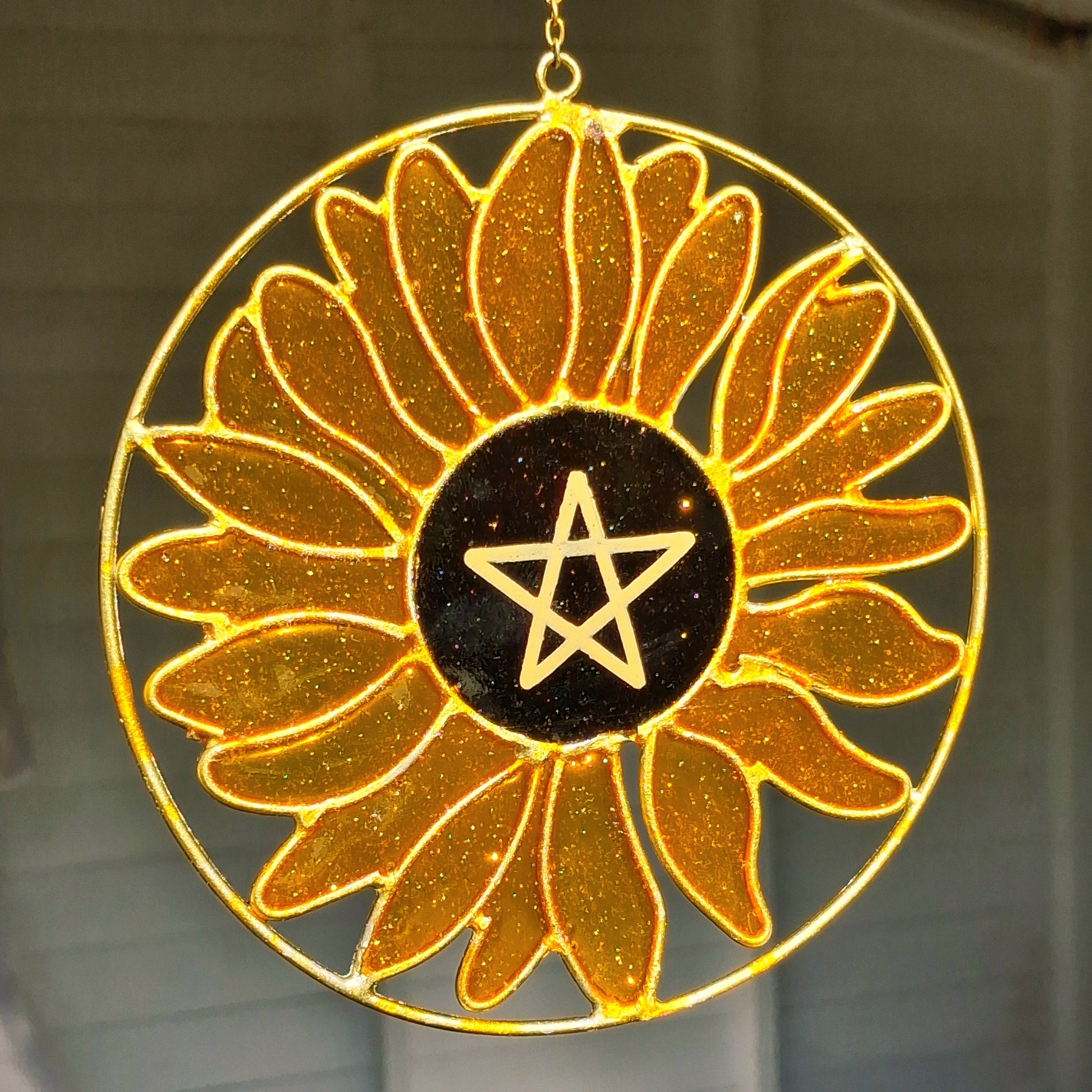 Add a touch of sunshine to the home with this Summer Solstice sunflower suncatcher. This charming suncatcher is inspired by the Summer Solstice, featuring a beautifully detailed sunflower, pentagram, star and crescent moon design made from metal and resin. Hang it in the window to catch the light and bring a cheerful, colourful glow to any room.