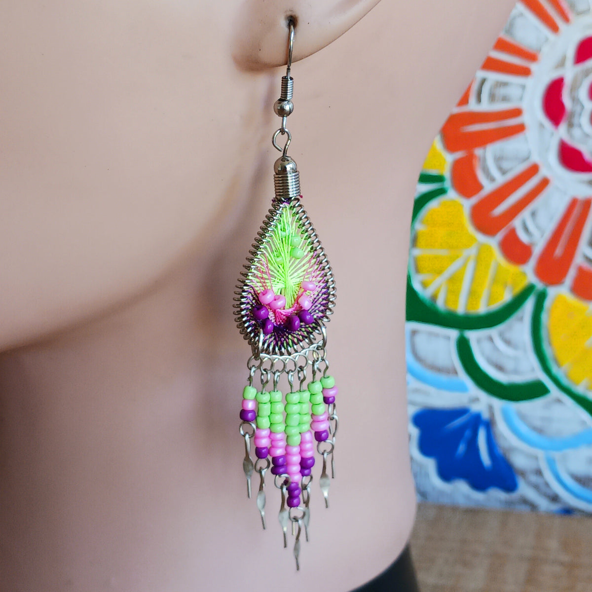 Add a splash of colour to your look with these beautiful handmade Peruvian woven teardrop earrings. Inspired by the vibrant colours and patterns of a peacock feather, each earring features intricate woven detailing complemented by coordinating beads and delicate silver-tone embellishments.
