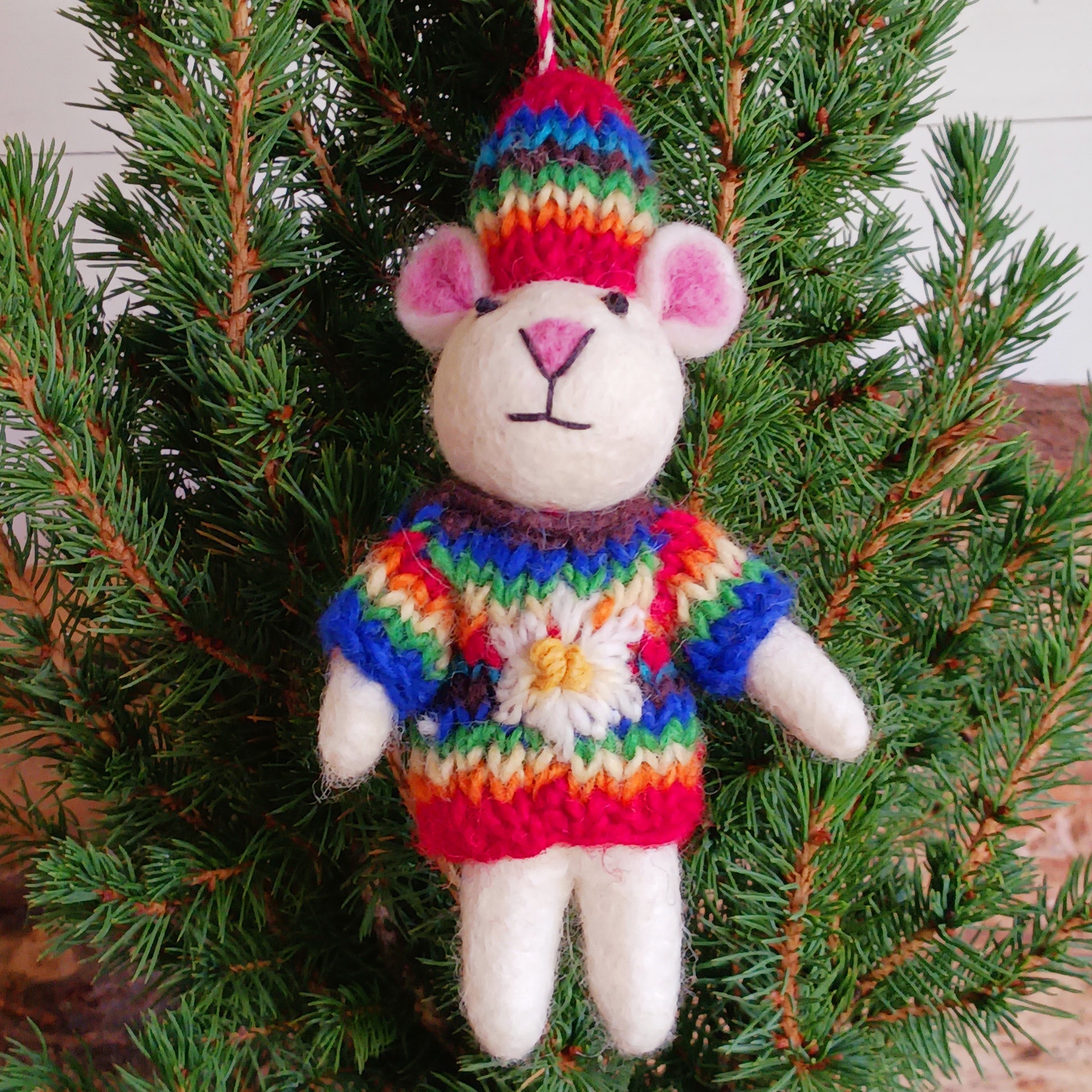 Bring instant festive cheer to your home with this adorable Christmas Tree Mouse Decoration. Dressed in a hand-knitted rainbow jumper and matching hat, this charming little mouse captures the magic of the season at first sight. Its sweet pink nose, expressive eyes, and cartoon-like ears bring out the childlike joy in anyone who sees it.