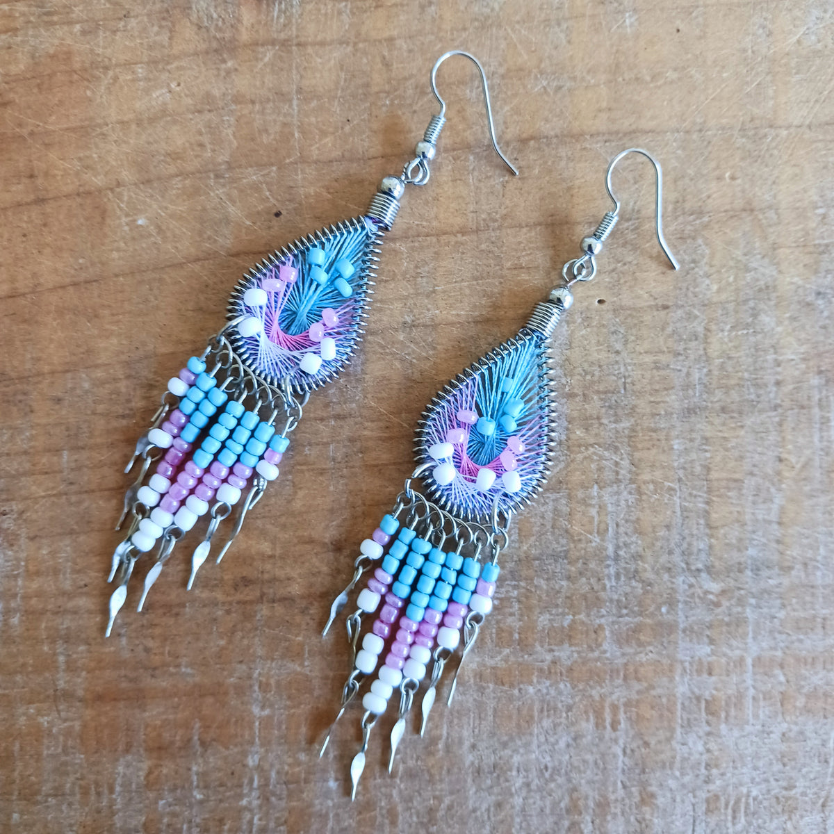 Add a splash of colour to your look with these beautiful handmade Peruvian woven teardrop earrings. Inspired by the vibrant colours and patterns of a peacock feather, each earring features intricate woven detailing complemented by coordinating beads and delicate silver-tone embellishments.