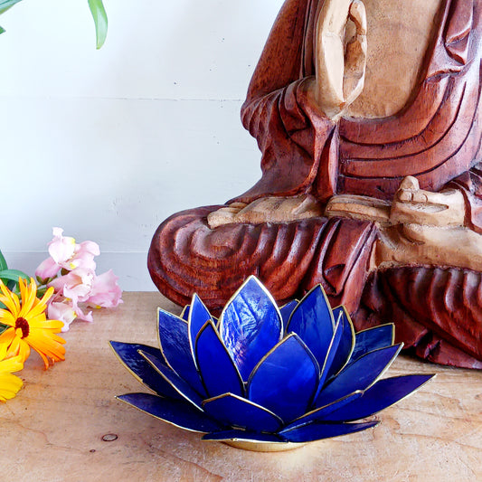 Illuminate your space with the peaceful elegance of our Capiz Shell Lotus Flower Candle Holder. Symbolizing enlightenment and serenity, this stunning handcrafted piece features delicate blue petals edged in gold, forming the iconic lotus shape.