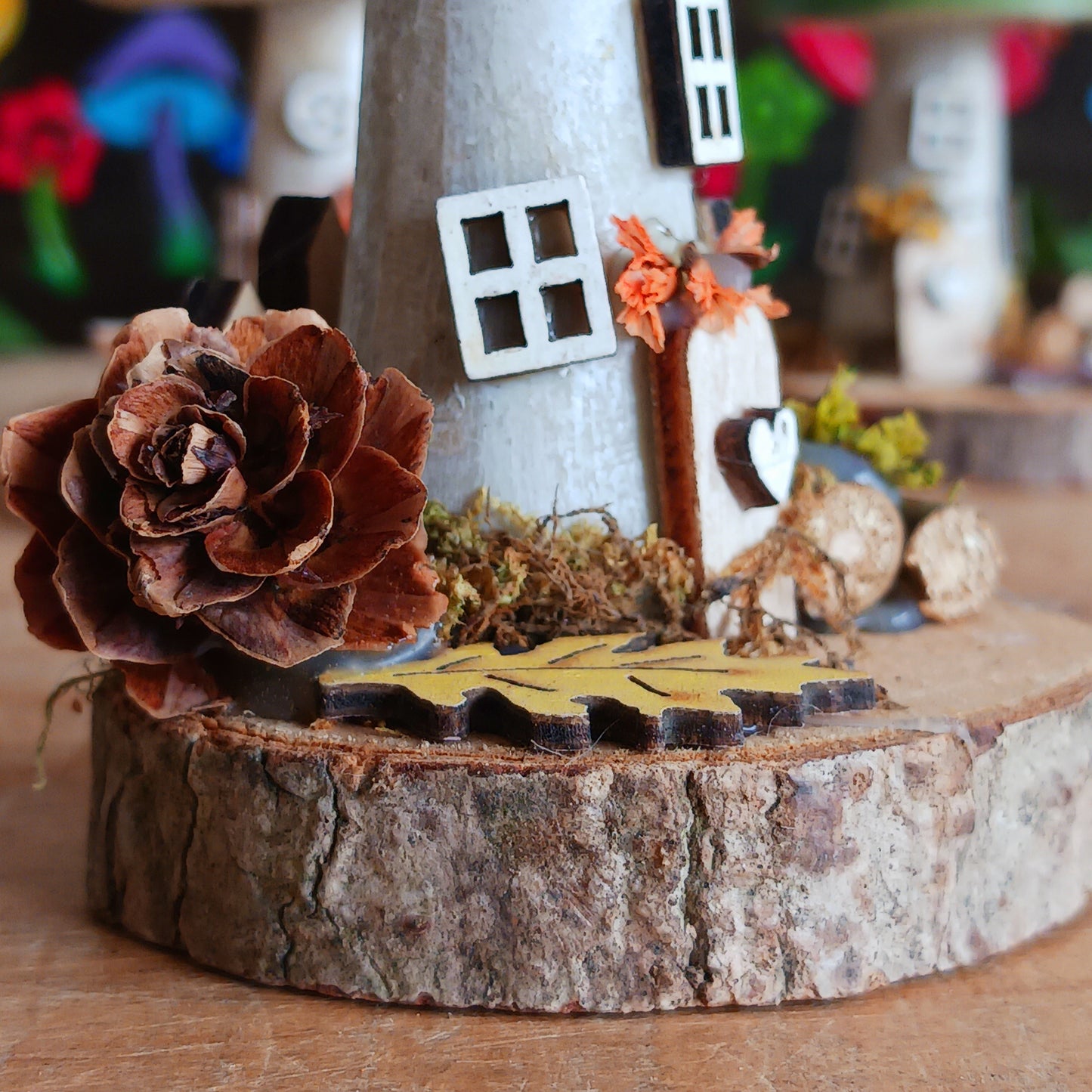 Decorative piece with a flower and small house on a wooden base