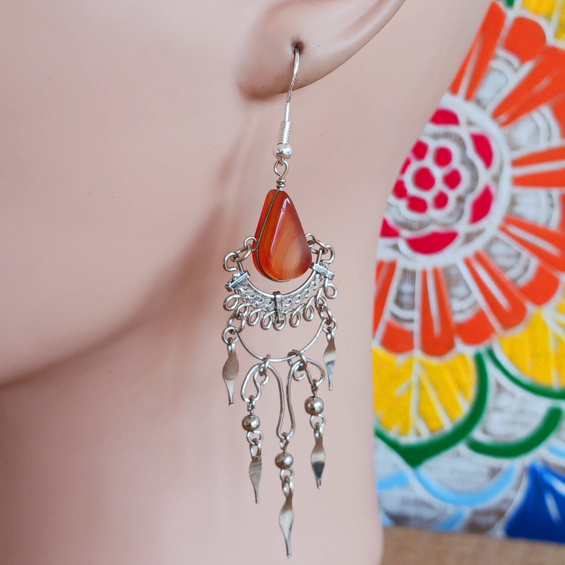 Add a touch of bohemian beauty to your look with these handmade Peruvian stone earrings. Featuring orange stones and finished with silver-plated hooks, each pair is carefully crafted in small workshops in Peru.