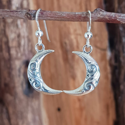 These exquisite sterling silver earrings feature a delicate Celtic spiral design beautifully interwoven in the crescent moon shape, symbolizing the waxing and waning phases. Crafted with fine attention to detail, each earring mirrors the other, representing balance in nature and the eternal cycles of life, growth, and renewal.
